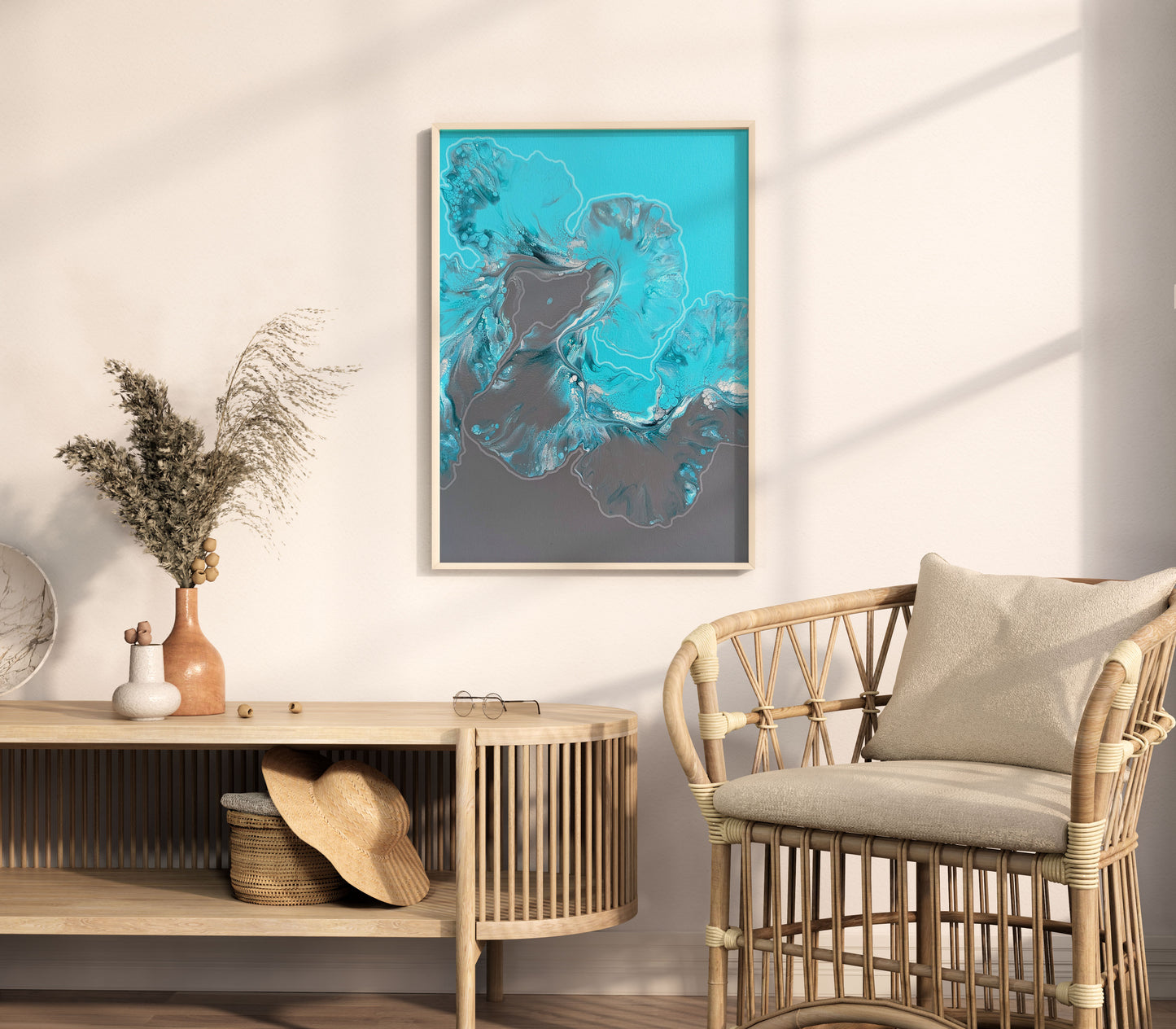Framed fluid acrylic painting with icy blue and gray tones, resembling abstract glacier formations, hanging on a neutral-toned wall above a curved wood console with vases, dried flowers, and a rattan chair in a sunlit room.