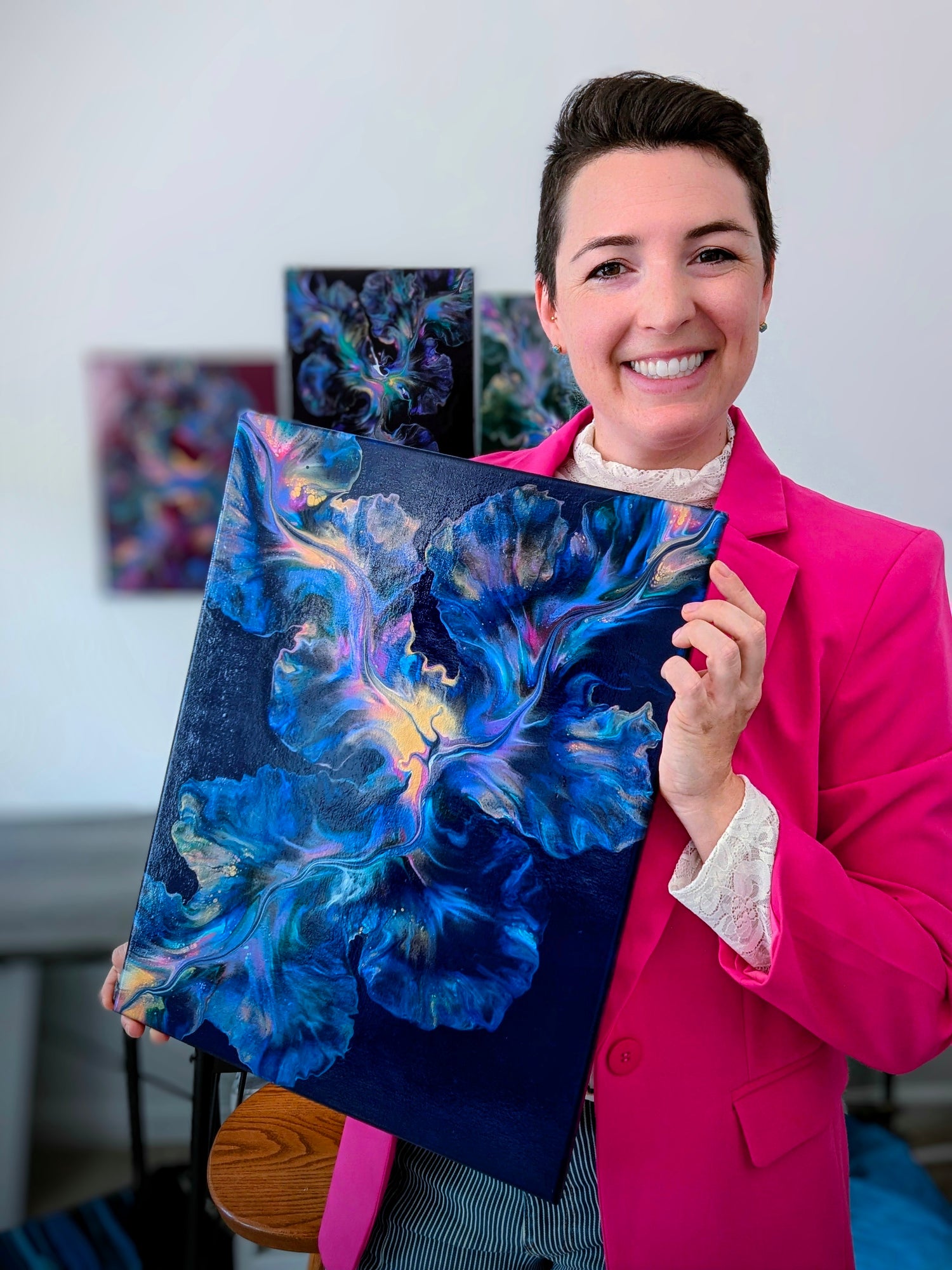 Artist Abby May with her painting Nebula Bloom in her studio with her other paintings behind her
