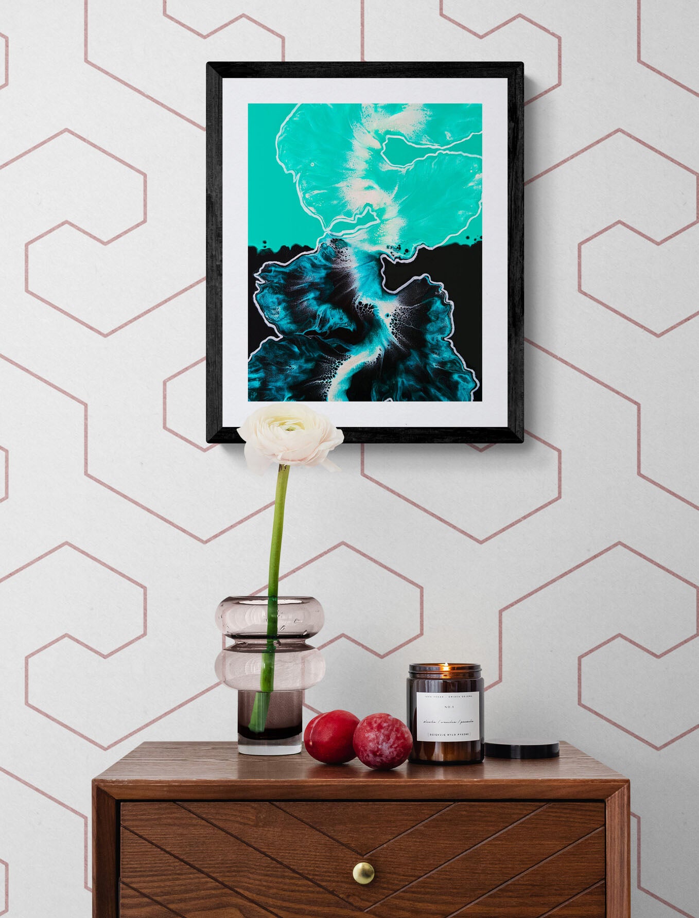 Between the Lines – teal and black abstract fluid painting print framed and styled on a wall with geometric pink accents above a wooden side table with candle, plums, and glass vase.