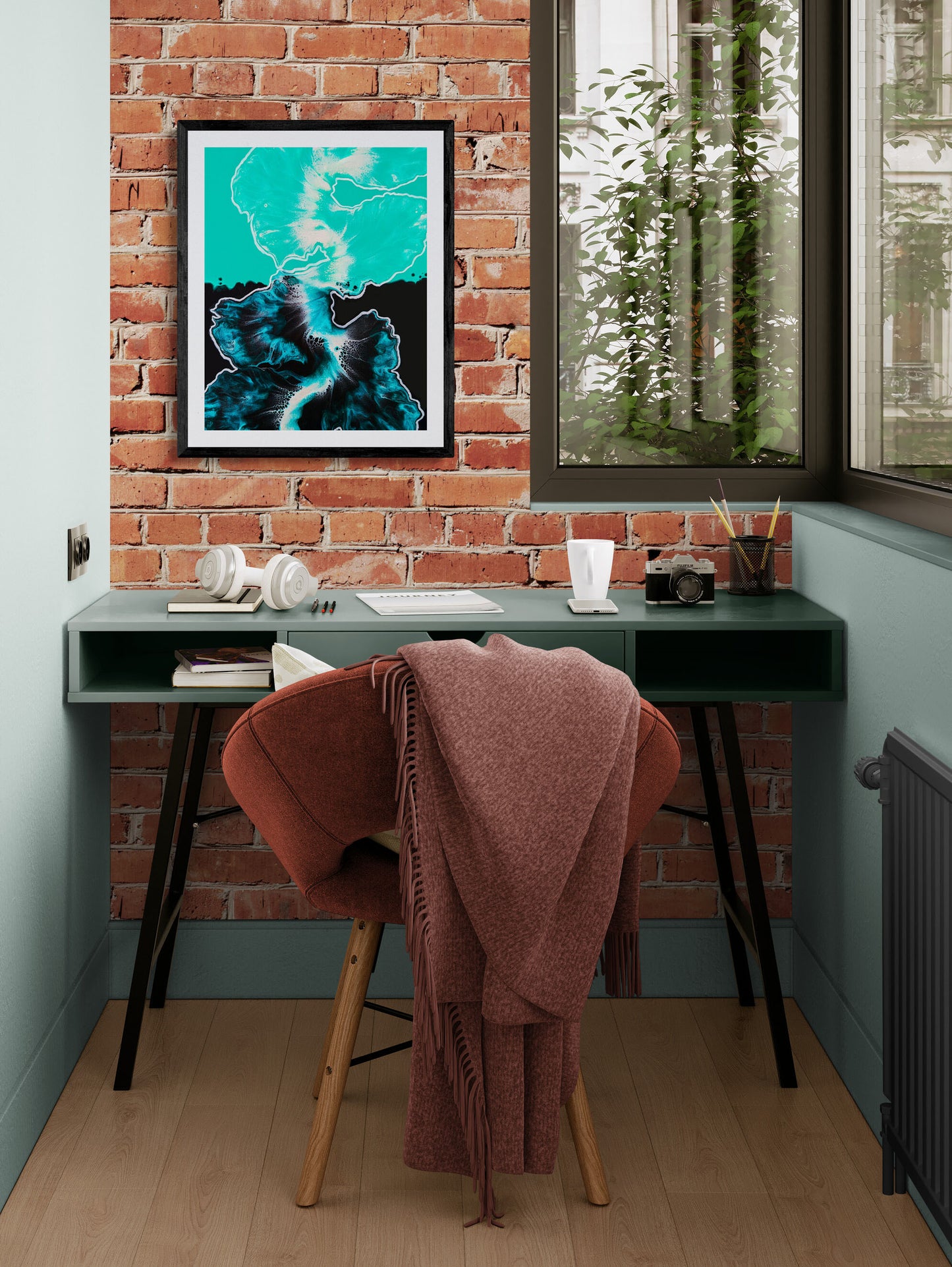 Between the Lines – bold teal and black acrylic fluid art print in a black frame displayed on an exposed brick wall above a desk with a terracotta chair and blanket.