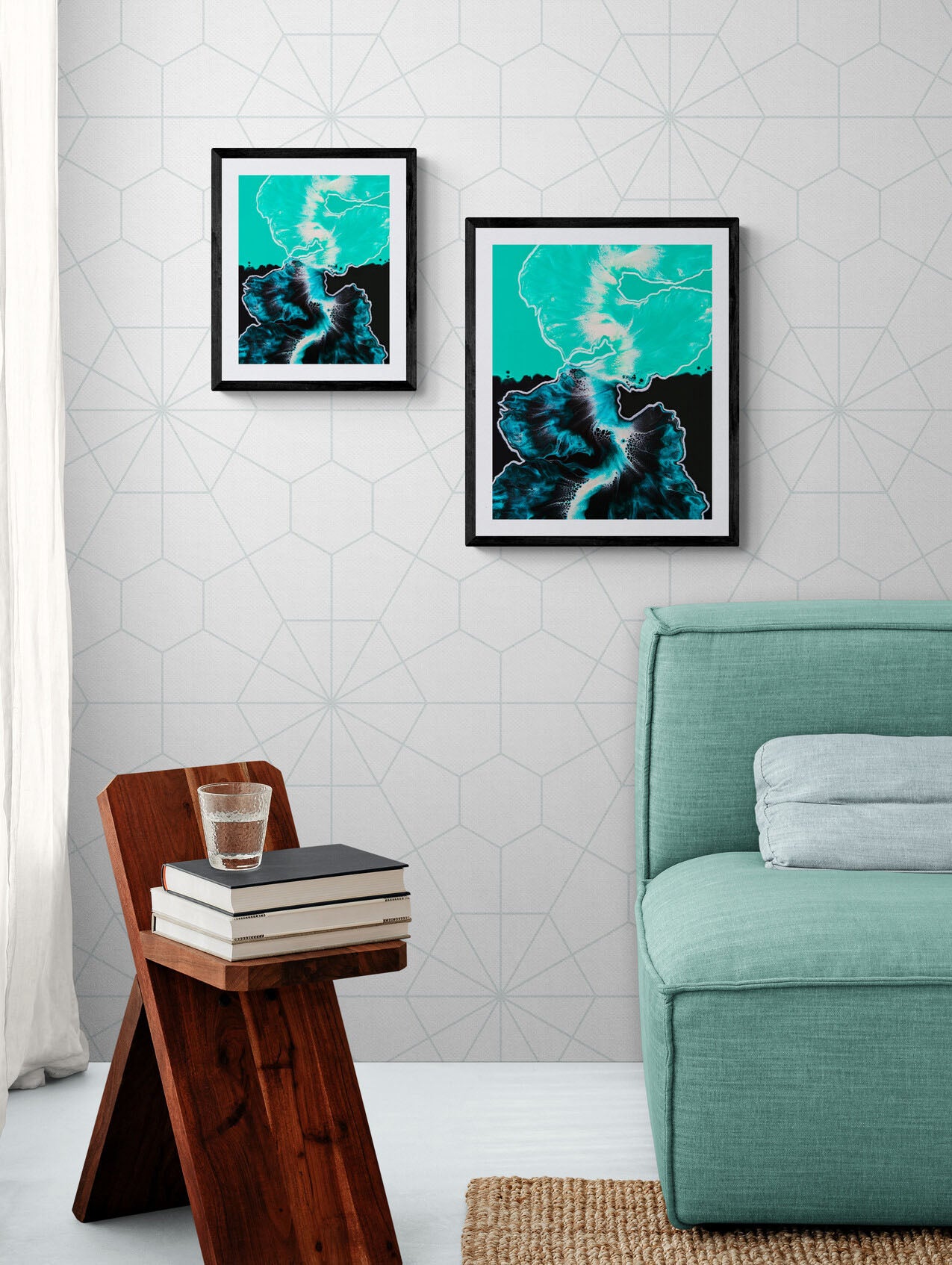 Between the Lines – framed teal, black, and white fluid art print hanging on a patterned wall above a modern side table with books and glass of water.
