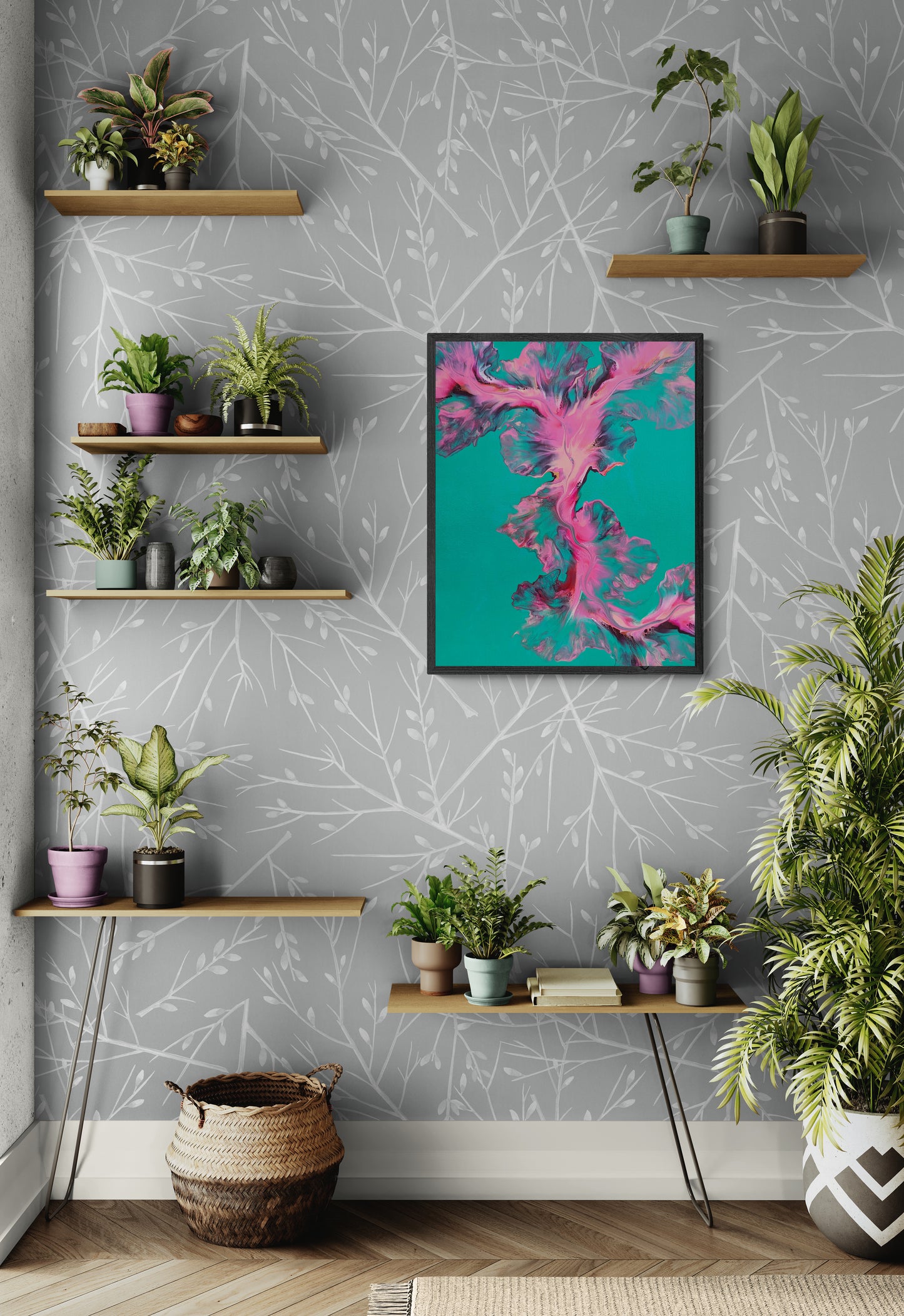 Framed abstract fluid painting featuring bright pink and blue swirls on a teal background, displayed on a soft gray botanical wallpapered wall surrounded by floating wood shelves filled with potted plants and books.