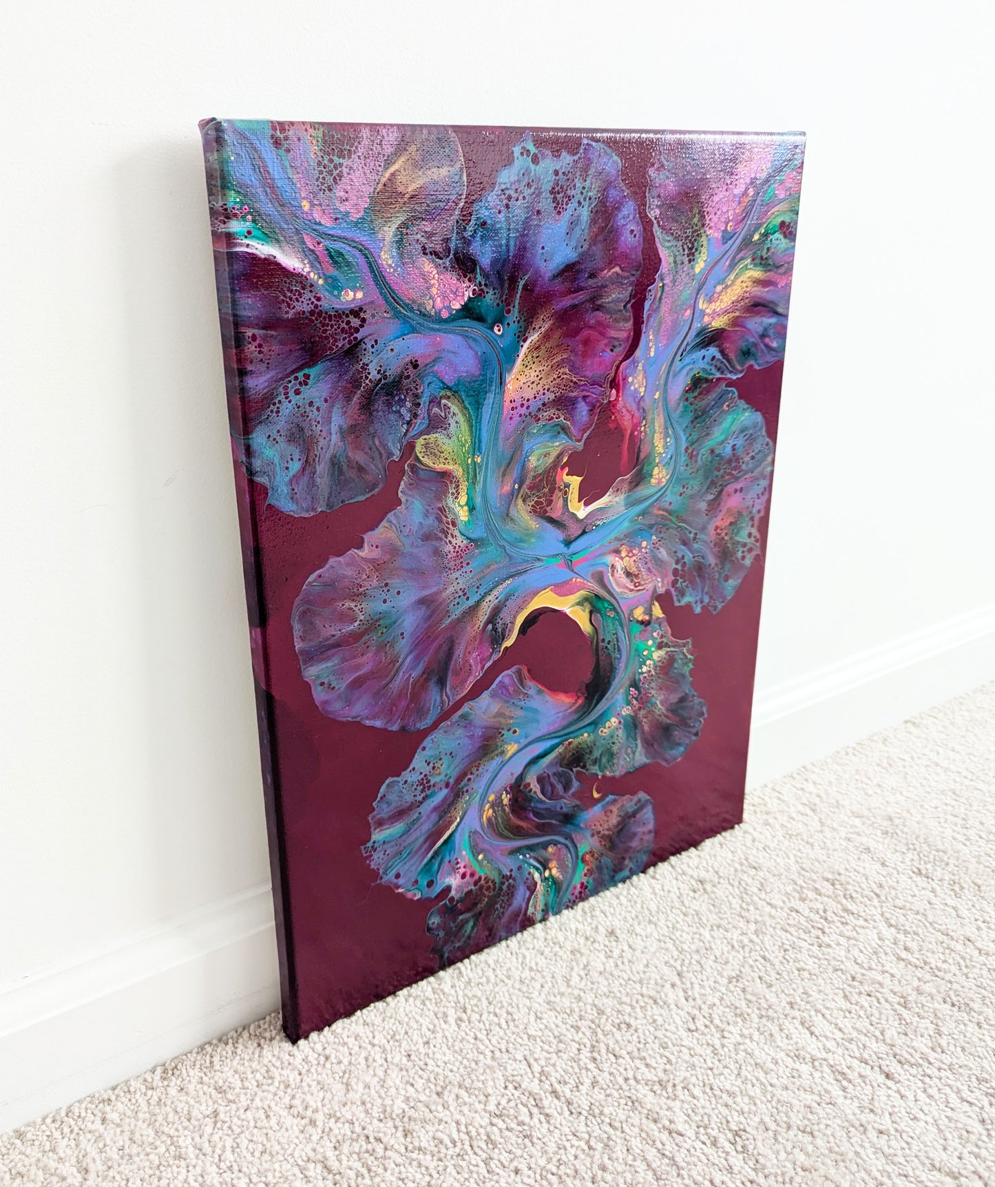 An expressive abstract fluid painting titled 'Ember Glow,' with a rich burgundy background illuminated by a vibrant blend of warm and cool tones. Fiery pinks and gold create a striking contrast, resembling glowing embers in motion
