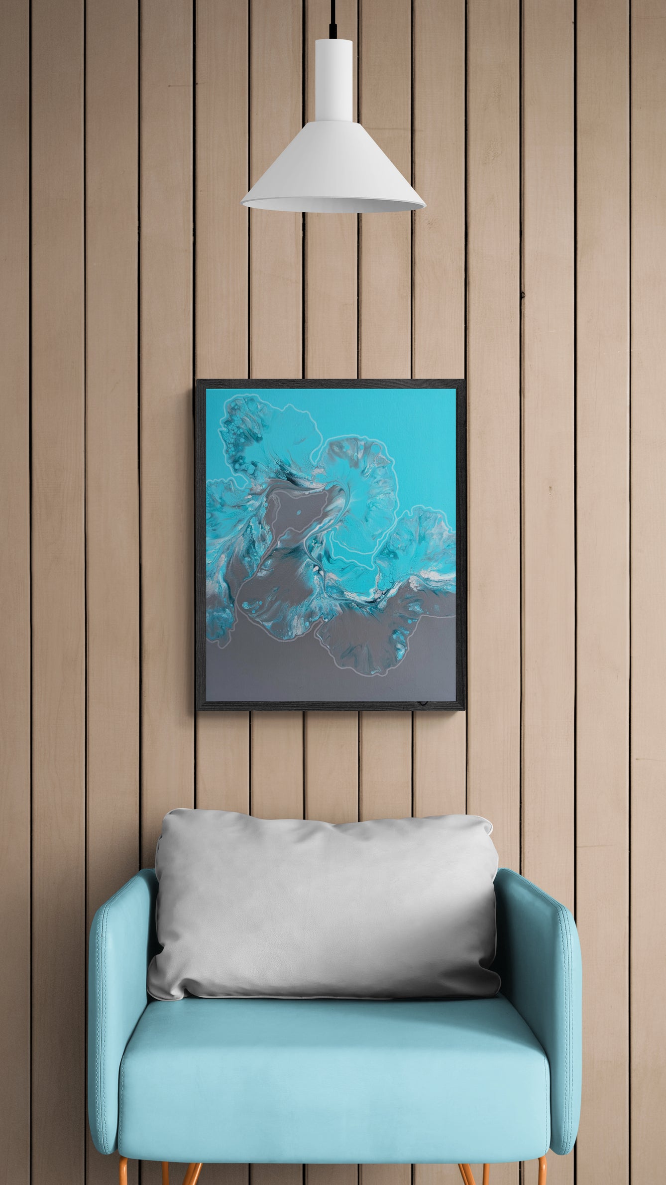 Framed fluid abstract painting with icy blue and gray tones hanging on a light wood paneled wall above a soft teal armchair with a gray pillow, under a white pendant light in a cozy modern interior.