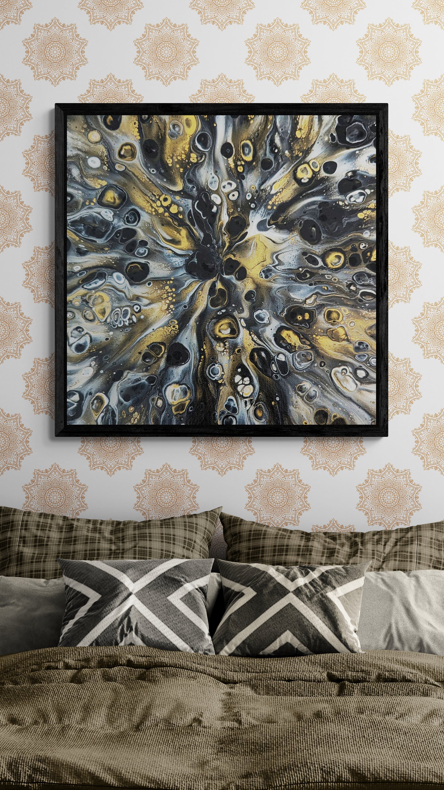 A framed abstract painting titled “Glamorous” hangs above a neatly made bed with earthy-toned pillows and blankets. The artwork features black, gold, and white fluid patterns radiating from the center, bringing a bold, sophisticated touch to the modern bohemian bedroom.