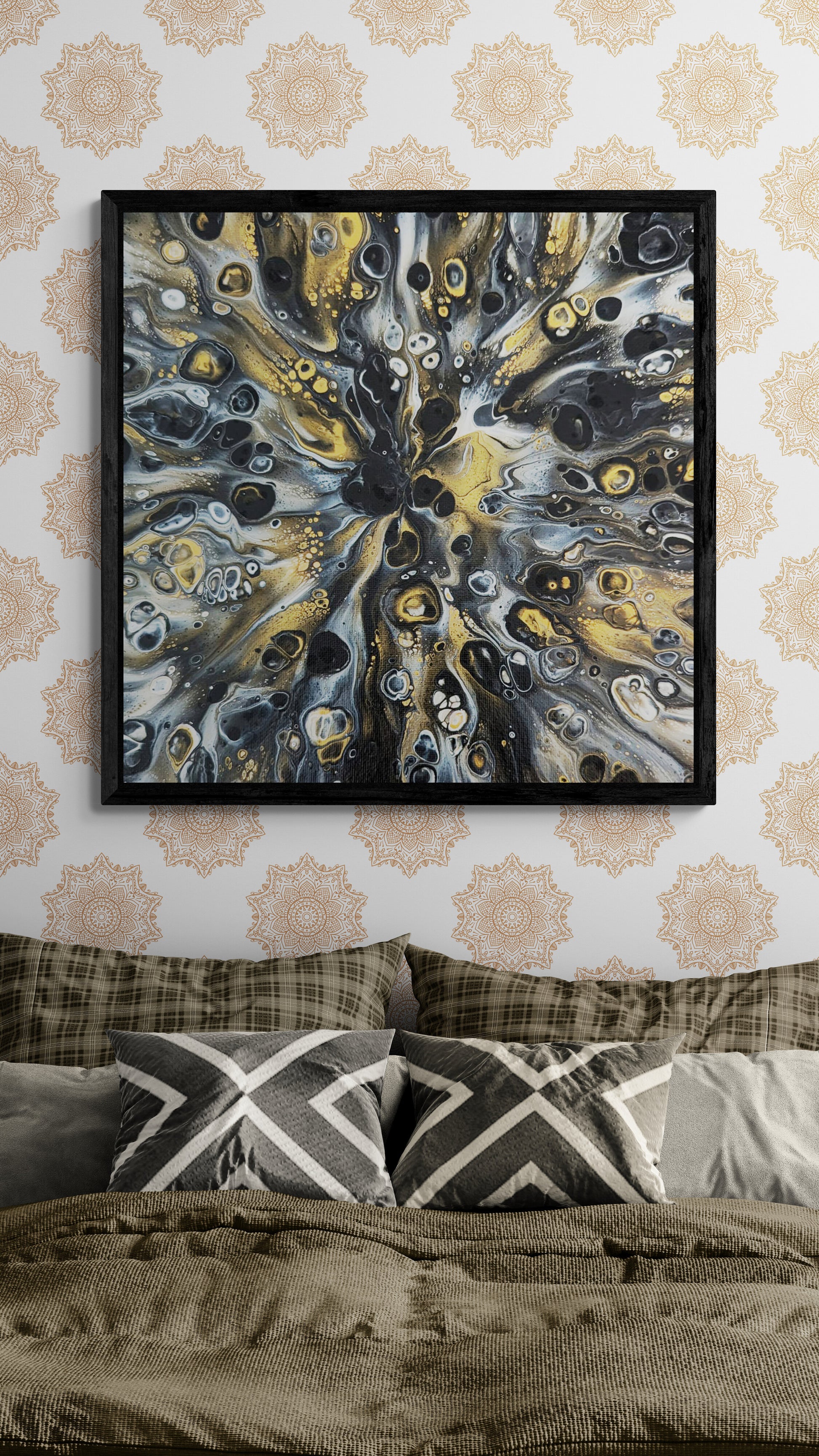 A framed abstract painting titled “Glamorous” hangs above a neatly made bed with earthy-toned pillows and blankets. The artwork features black, gold, and white fluid patterns radiating from the center, bringing a bold, sophisticated touch to the modern bohemian bedroom.