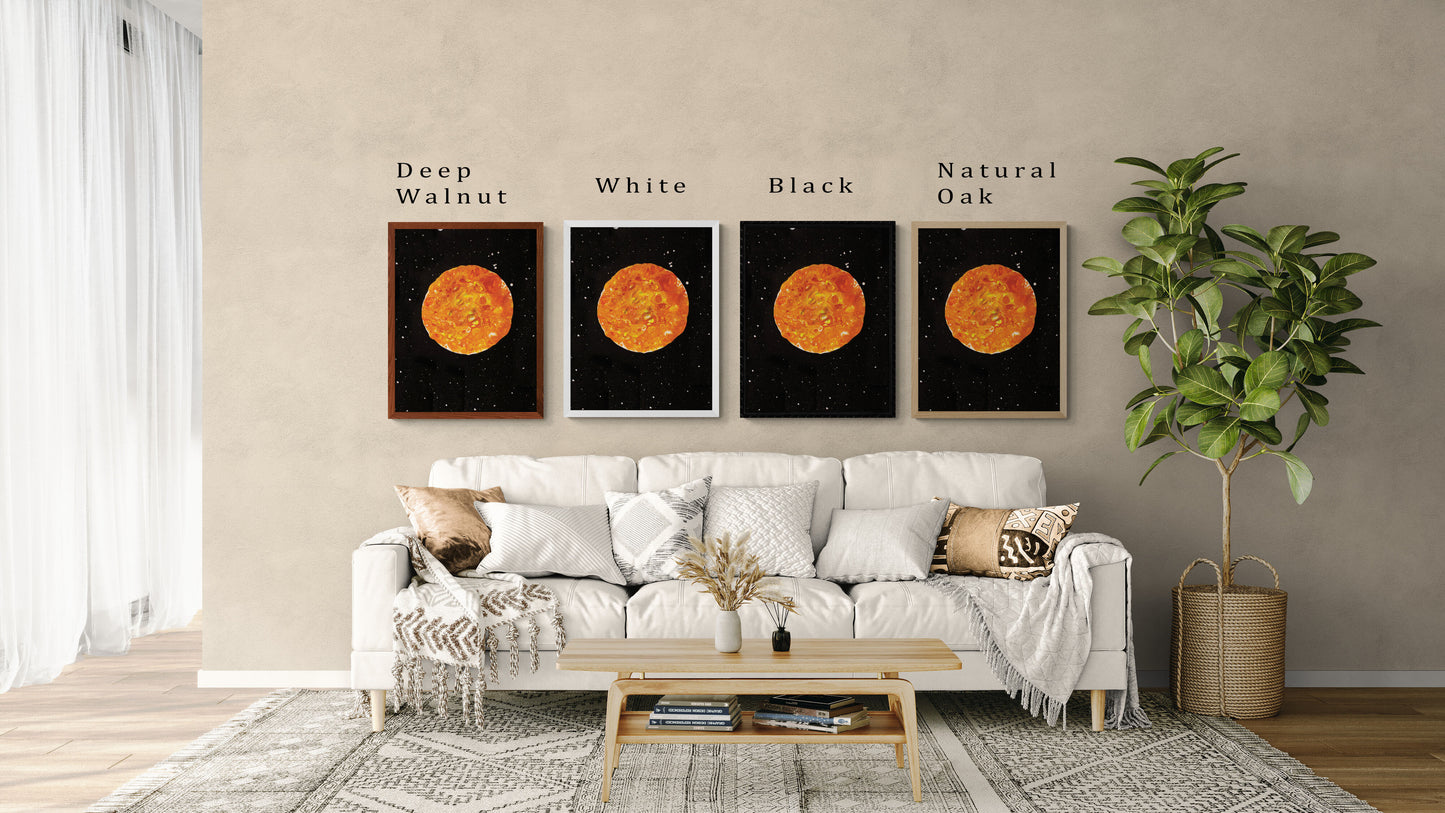 Four framed prints of Abby May Art’s painting “Harvest Moon” displayed above a cozy cream-colored sofa in a modern living room. The artwork features a glowing orange and golden-yellow moon with textured fluid patterns, set against a black starry night sky. Each frame shows a different color option—Deep Walnut, White, Black, and Natural Oak—with labels above each. Neutral pillows, a woven throw, a wooden coffee table, and a potted plant complete the space, helping customers visualize how the art will look in