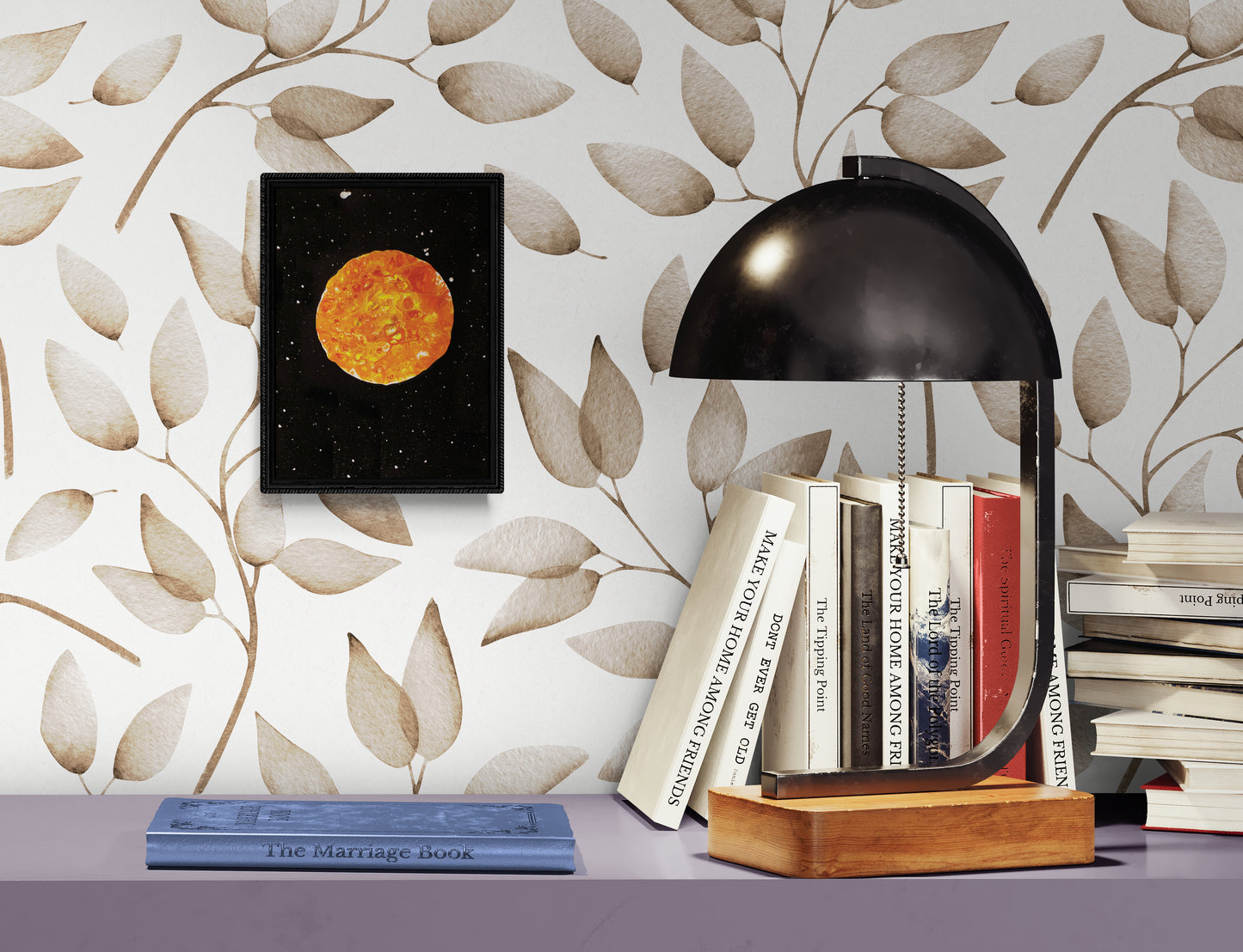 Harvest Moon art print displayed in a black frame against a soft leaf-patterned wallpaper, styled with books and a modern lamp