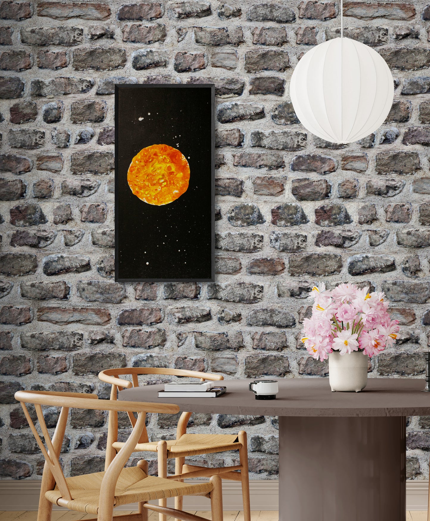 Tall framed Harvest Moon artwork hanging on a stone wall above a dining table, styled with flowers and wooden chairs for a rustic modern look.
