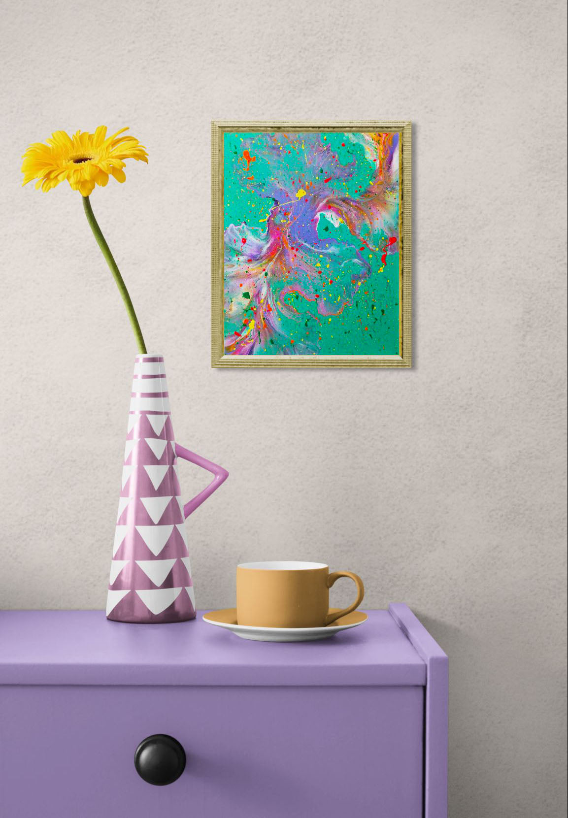 'Have You Lost Weight?' painting displayed in a gold frame on a textured wall above a lavender console table, next to a yellow flower in a pink and white geometric vase and a mustard yellow teacup.