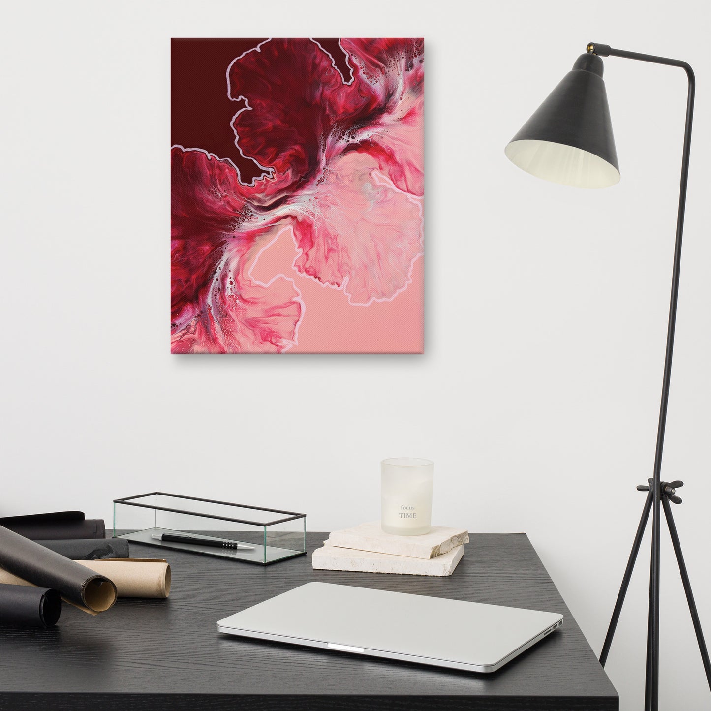 "Hold The Line" acrylic fluid art canvas print without frame, displayed on a white wall above a modern black desk with lamp, showing bold red and pink abstract swirls with white highlights.