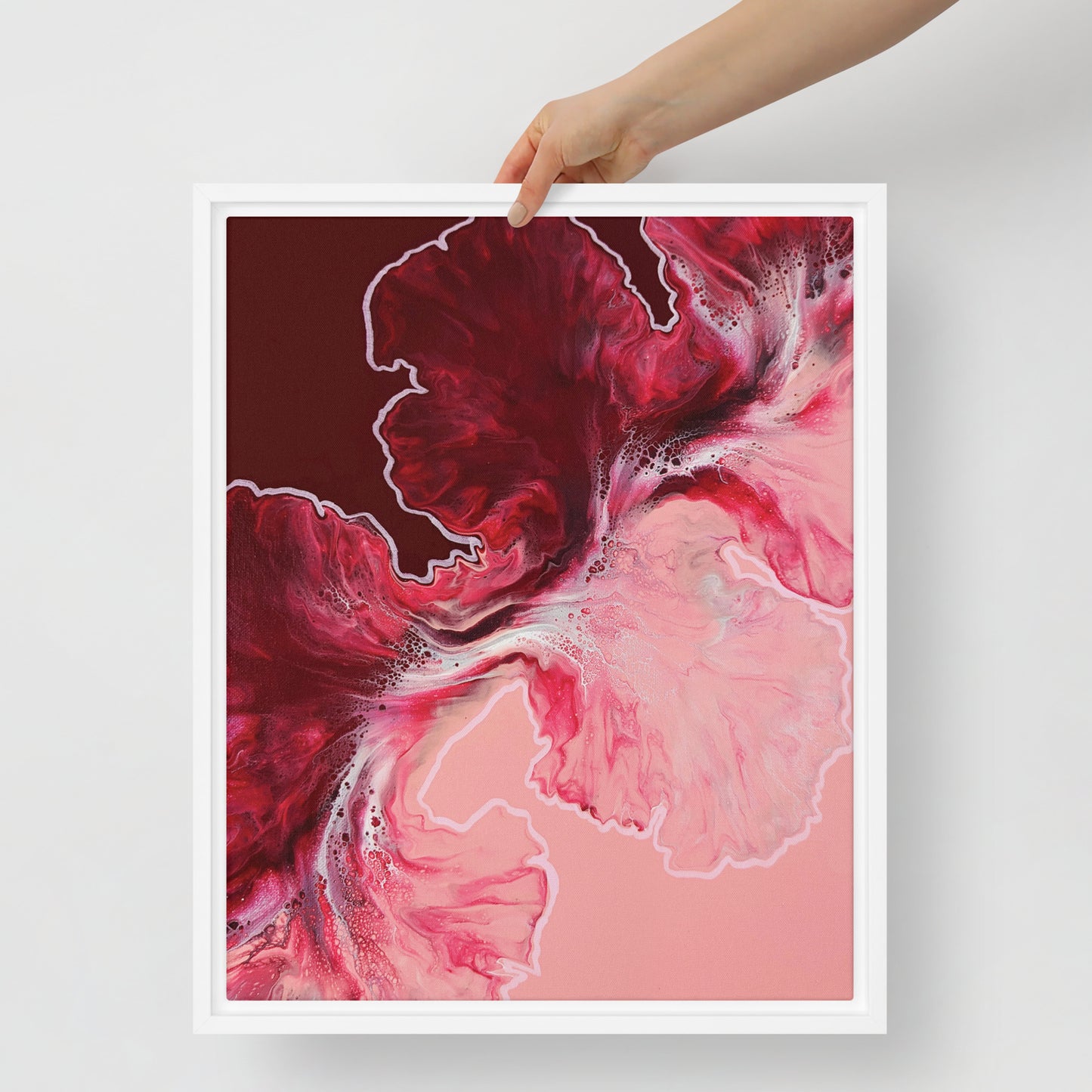 "Hold The Line" acrylic fluid art canvas print in a white floating frame, held up to show scale, featuring bold red and pink abstract swirls with white accents.