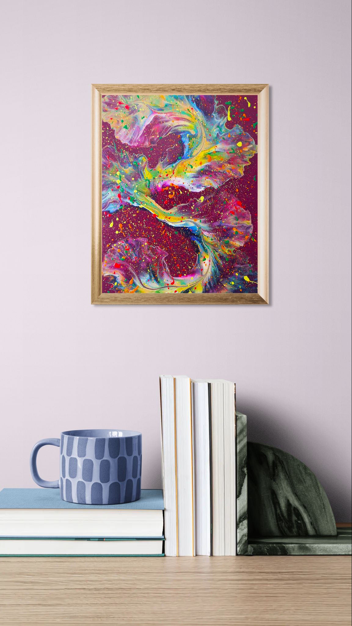 'I Wish I Had Your Confidence' painting in a gold frame on a lavender wall, placed above stacked books and a soft blue patterned mug for a cozy, colorful aesthetic.
