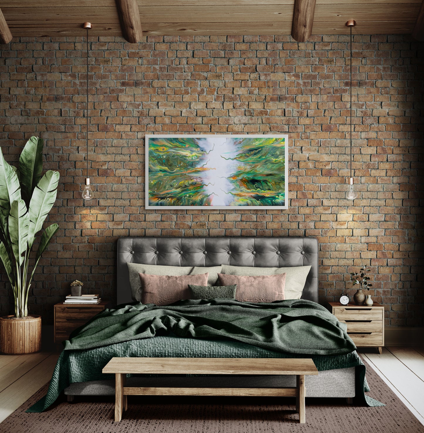 A framed abstract fluid canvas print titled “Lush” hangs above a tufted gray headboard in a cozy bedroom with exposed brick walls, green bedding, and soft pink accent pillows. The painting features swirling greens, yellows, and oranges converging toward a bright white center, adding organic energy to the warm, earthy space.