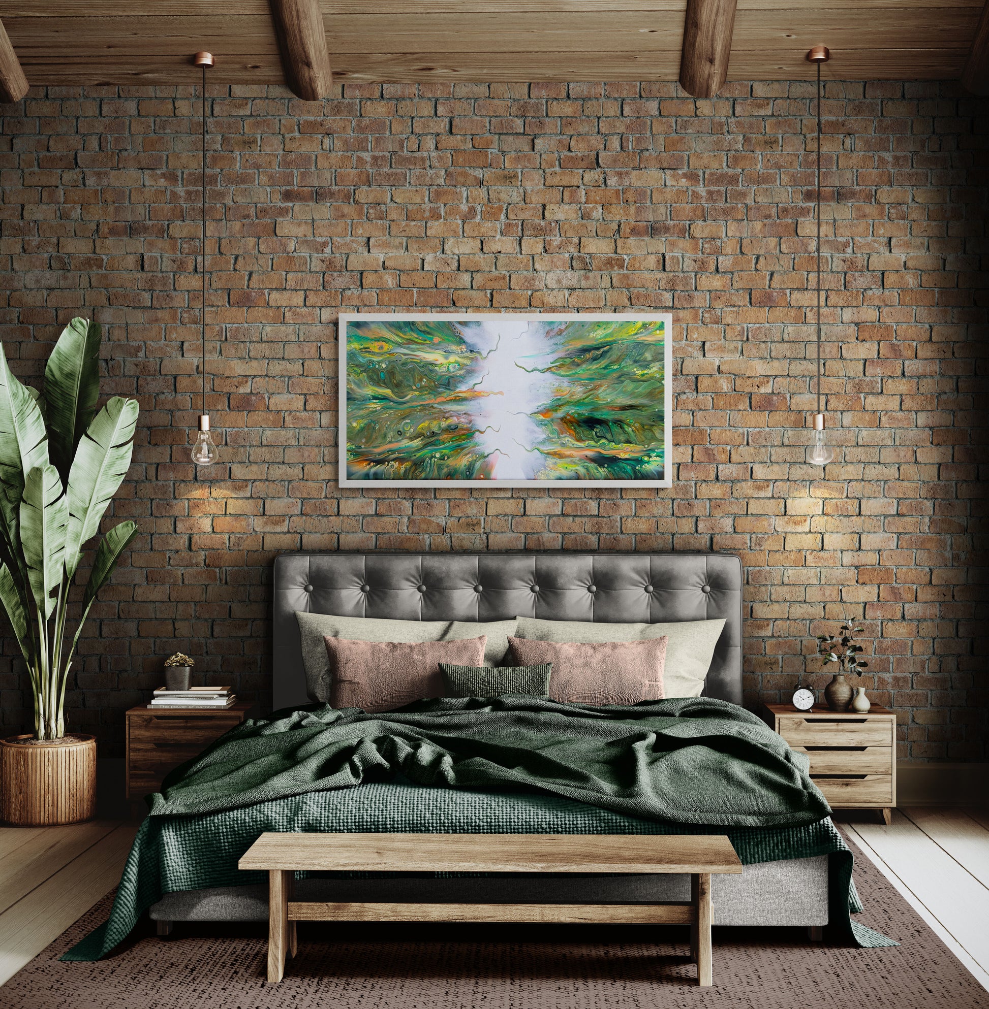 A framed abstract fluid canvas print titled “Lush” hangs above a tufted gray headboard in a cozy bedroom with exposed brick walls, green bedding, and soft pink accent pillows. The painting features swirling greens, yellows, and oranges converging toward a bright white center, adding organic energy to the warm, earthy space.