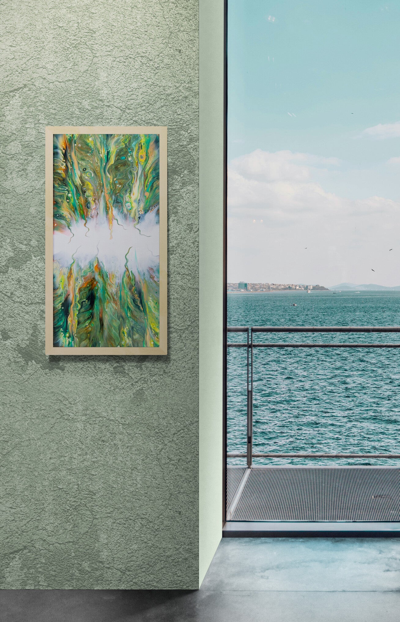 The canvas print “Lush” is displayed vertically on a textured green wall beside a large window overlooking the ocean. The piece’s dynamic greens, yellows, and white central burst echo the natural scenery outside, blending art with the tranquil coastal view.