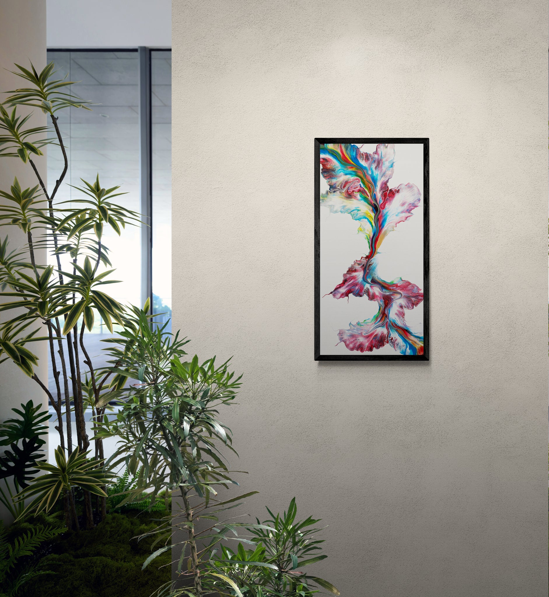 A vibrant abstract painting titled "Macaw" is framed in black and displayed on a soft beige wall. The artwork features sweeping ribbons of red, teal, yellow, and cobalt over a white background, arranged in a vertical flow that mimics wings mid-flight. Surrounding the painting are lush green indoor plants, adding a natural, tropical touch to the serene, modern interior.