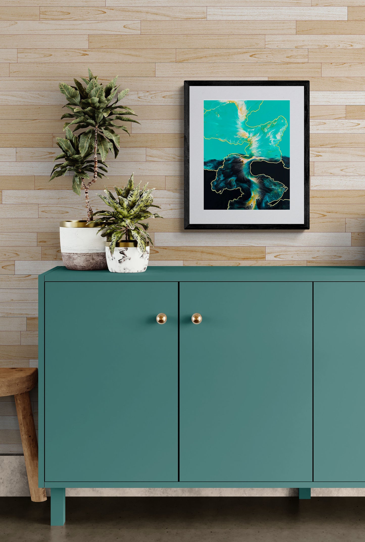 Framed teal, black, and metallic gold fluid art print styled above a modern green cabinet with indoor plants.
