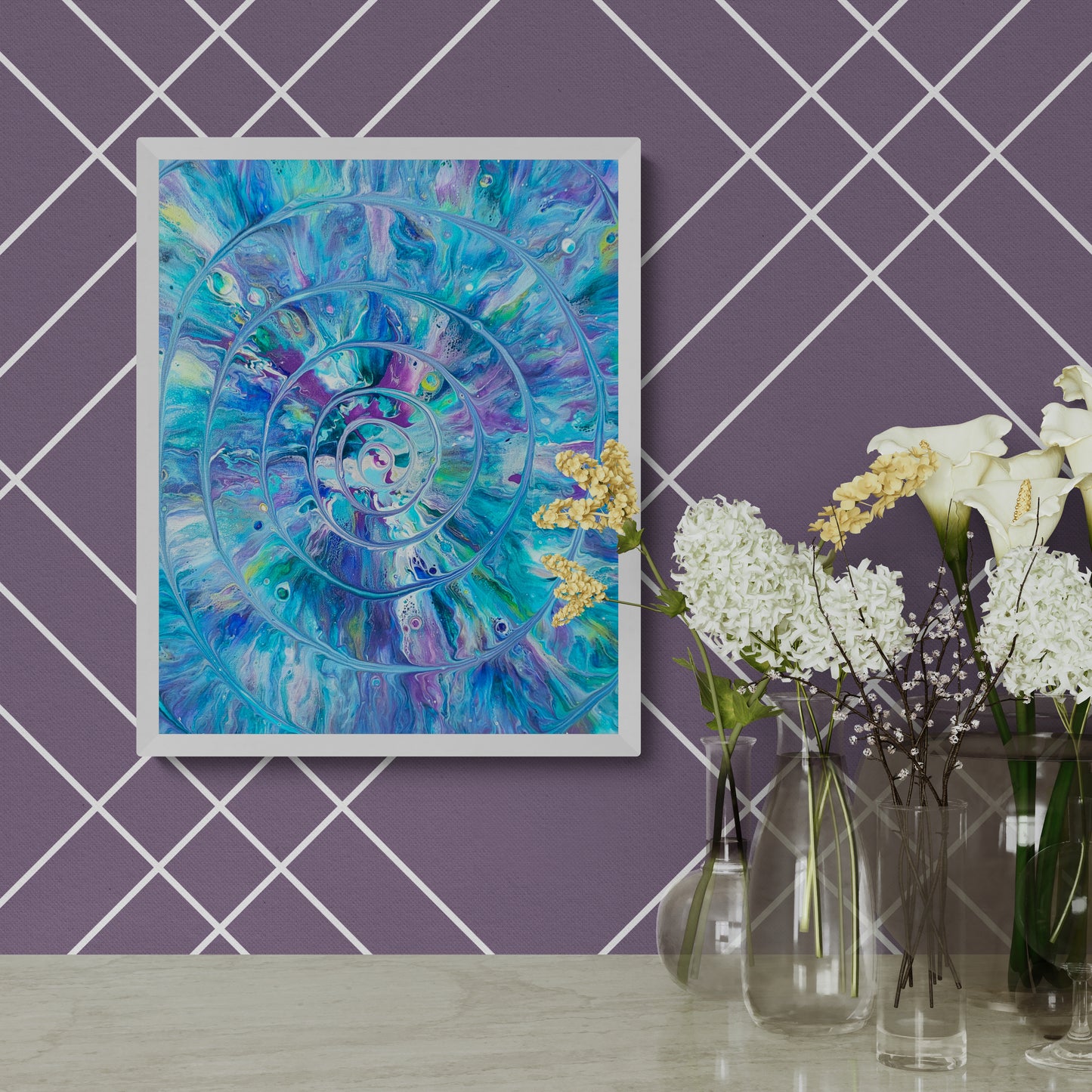 Framed abstract painting with a turquoise, blue, purple, and white spiral design hanging on a purple wall with white grid pattern; positioned above a stone surface with a variety of clear glass vases and delicate white, yellow, and purple flowers.