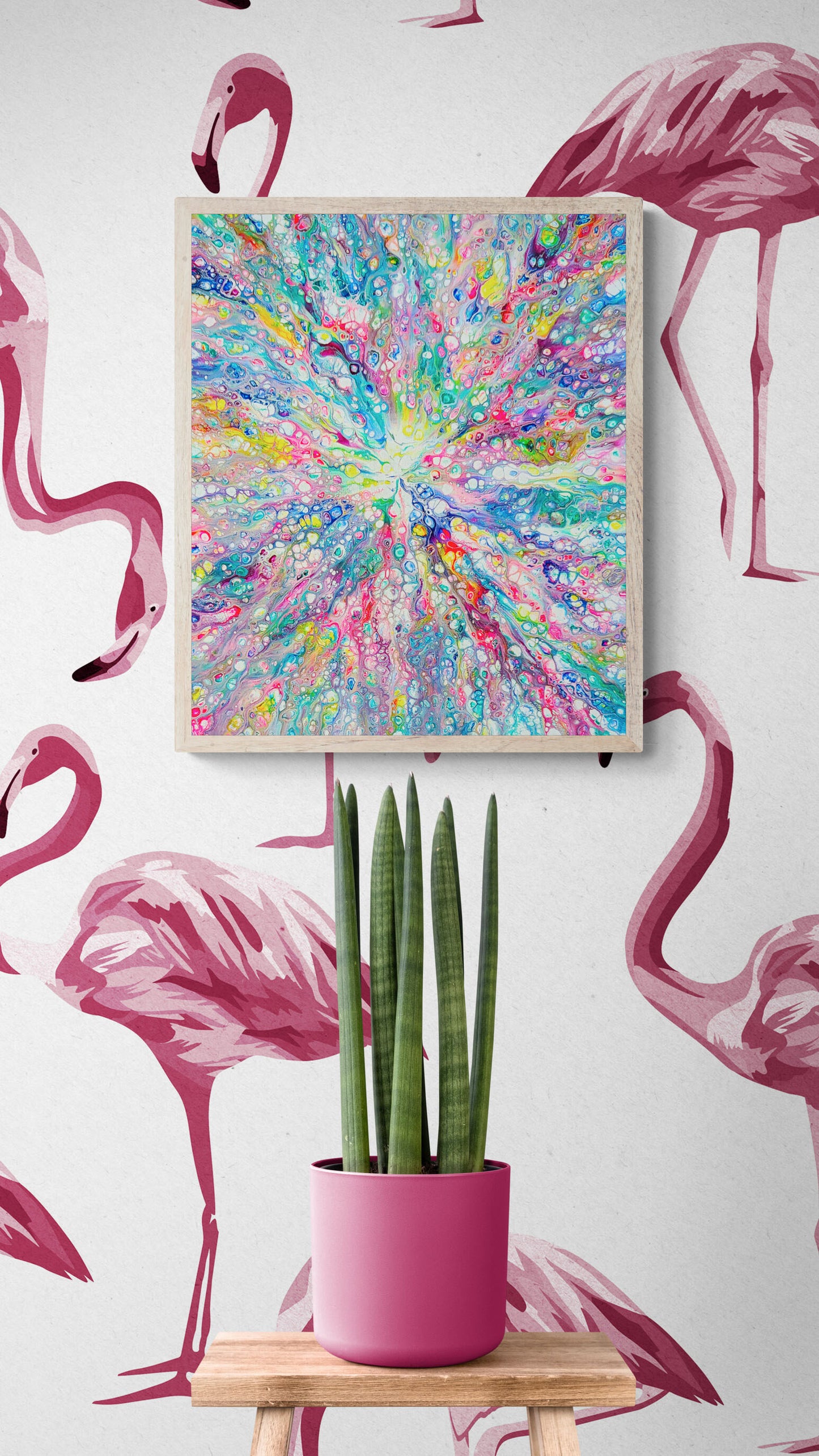 Rainbow Dragon acrylic fluid art print in bright rainbow tones, framed above a pink planter with tall green plant against flamingo wallpaper.