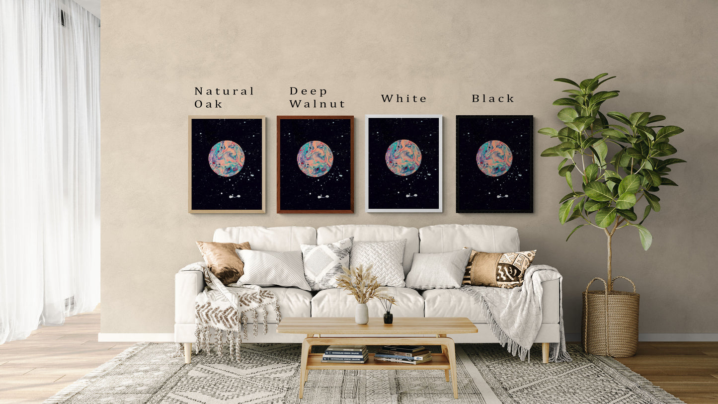 Four framed prints of Abby May Art’s “Strawberry Moon” painting displayed above a neutral cream sofa in a cozy modern living room. The artwork features a pink, teal, and lavender marbled moon against a black starry sky with subtle white speckles. Each print is shown in a different frame color—Natural Oak, Deep Walnut, White, and Black—with labels above each frame. The scene includes neutral throw pillows, a light wood coffee table, and a tall potted plant, helping viewers visualize the artwork in a real hom
