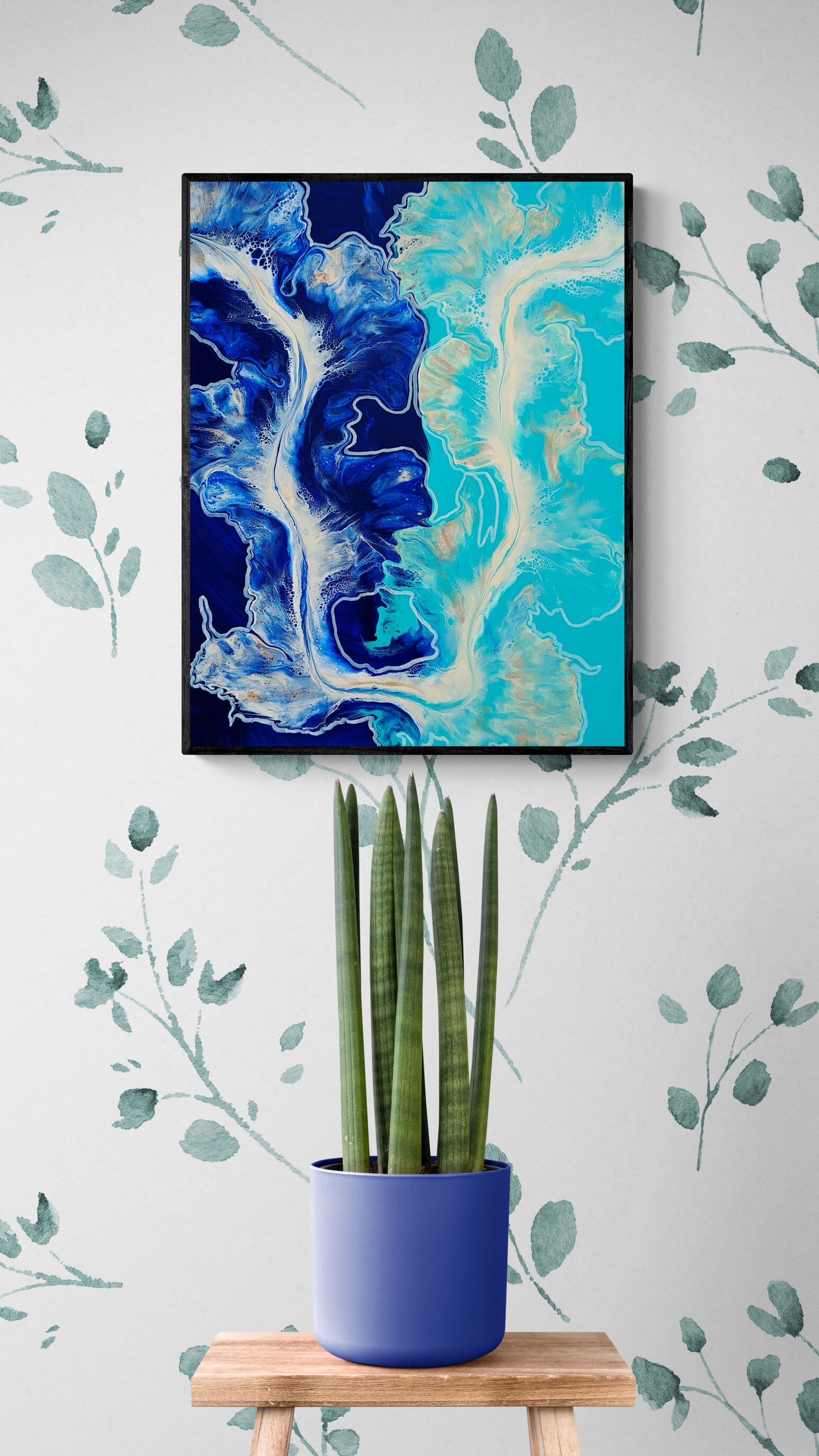 The Fine Line – ocean-inspired abstract fluid art print in bold navy and turquoise, framed wall art styled above wooden stool with tall green plant.