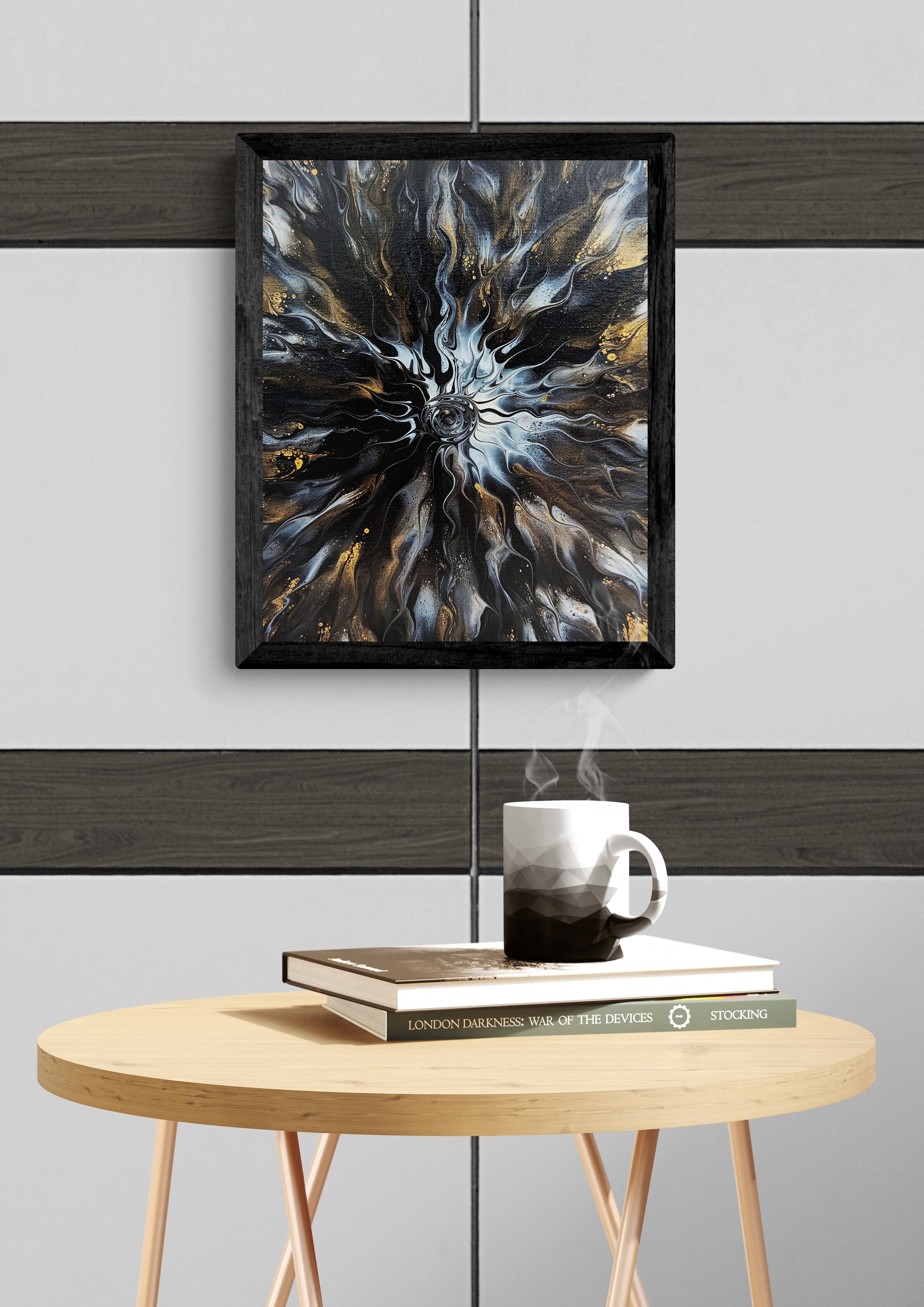 Abstract fluid art print in black, gold, and gray framed in black, displayed above a round wood table with a steaming mug and stacked books