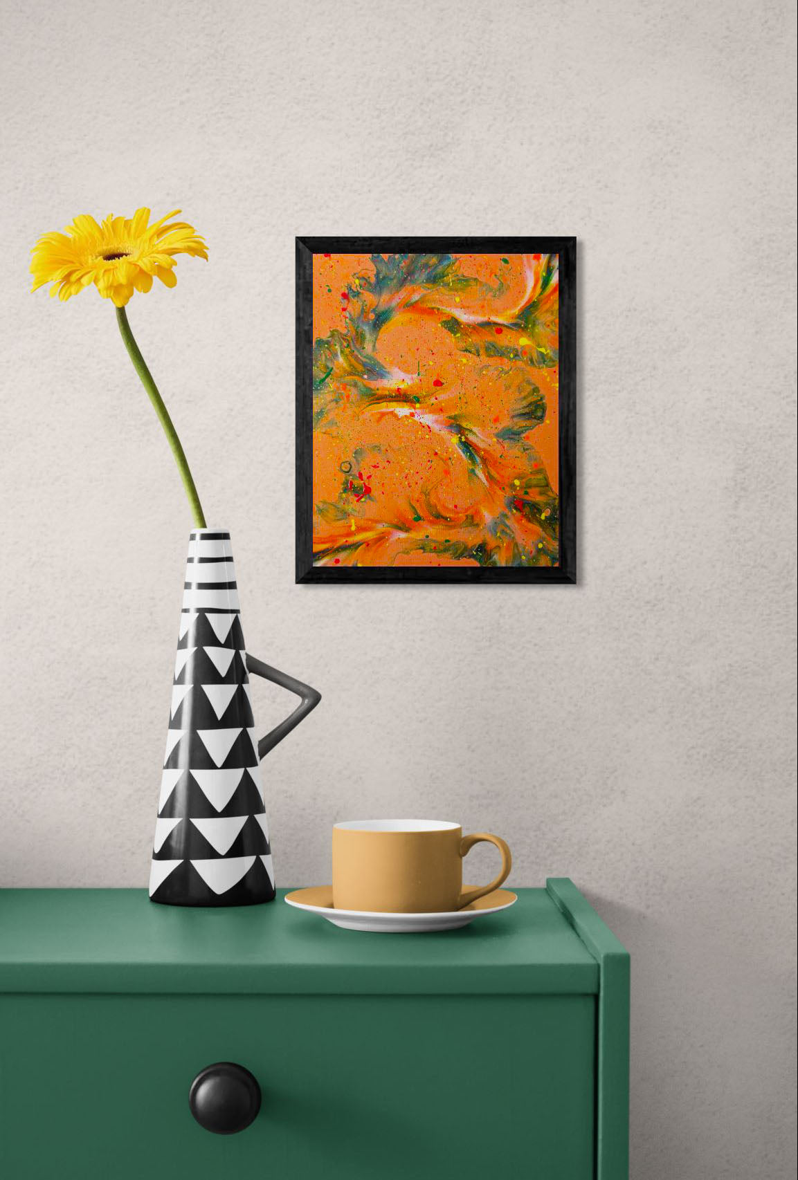 'Are You Really Going Out in That?' painting displayed in a black frame on a textured wall above a green console table, next to a yellow flower in a black and white geometric vase and a mustard yellow teacup.