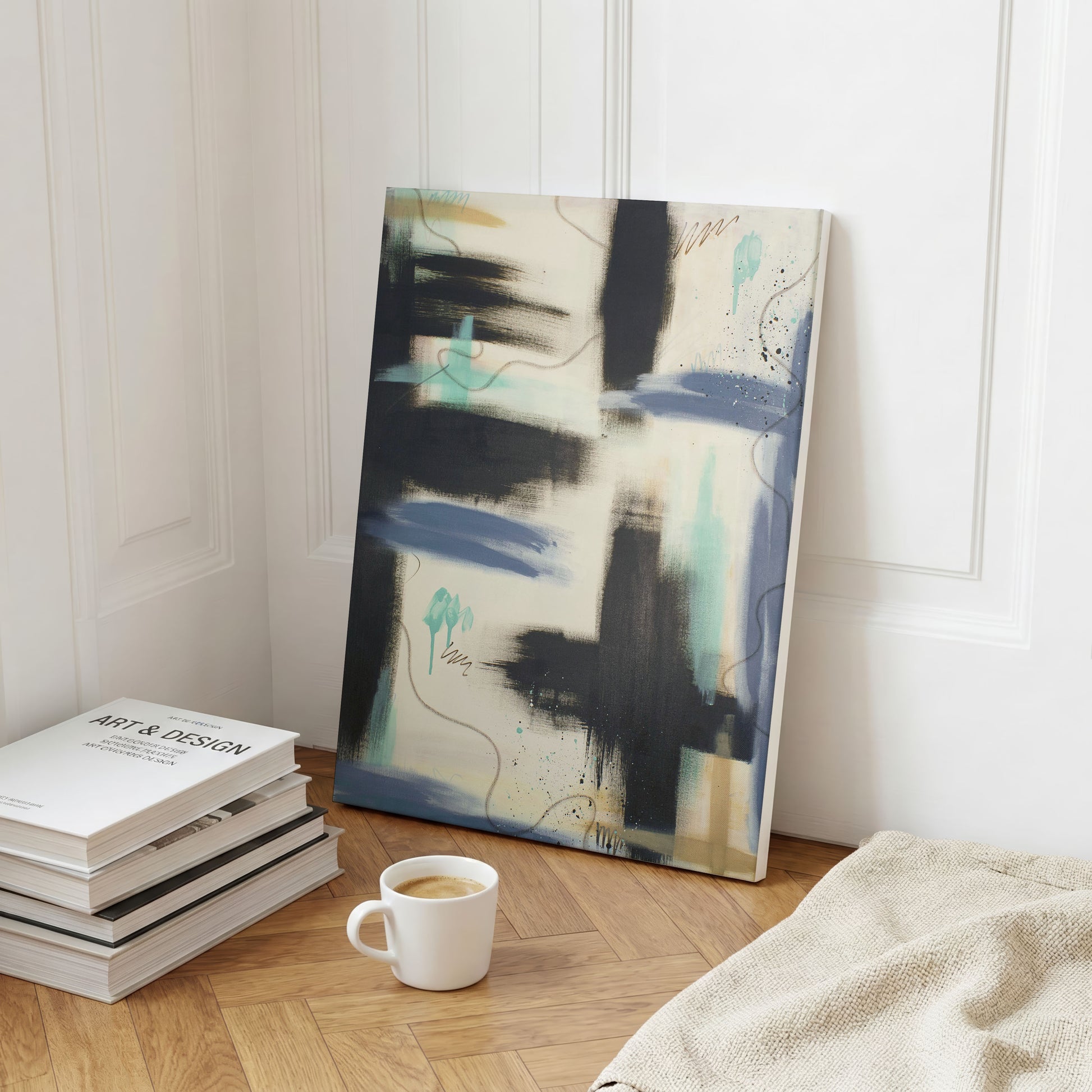 A canvas print of the painting sitting on a wooden floor, leaning against a white wall. In front of the print is a stack of books, a coffee cup, and a threaded blanket.