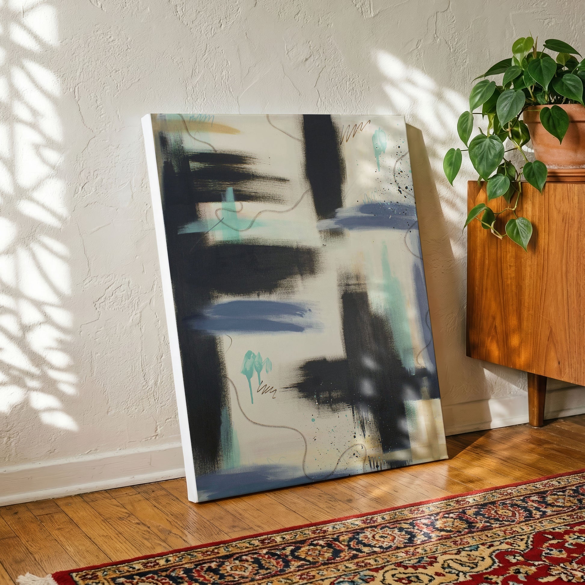 A canvas print of the painting sitting on a wooden floor, leaning against a textured white wall. In front of the print is a patterned rug, and to the right is a wooden side table with a potted house plant.