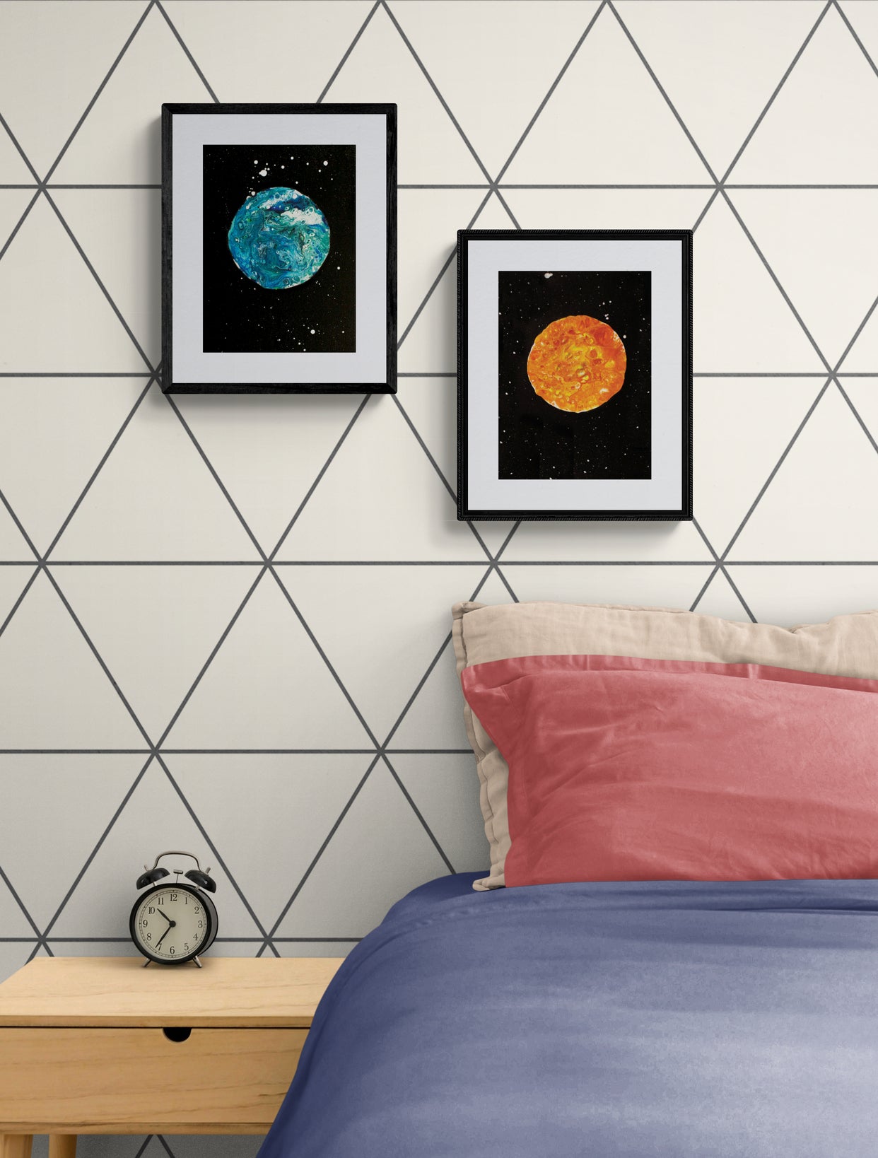 Blue Moon and Harvest Moon art prints displayed in black frames above a bedside table with a vintage alarm clock and mauve pillow on a bed; geometric wallpaper in the background.