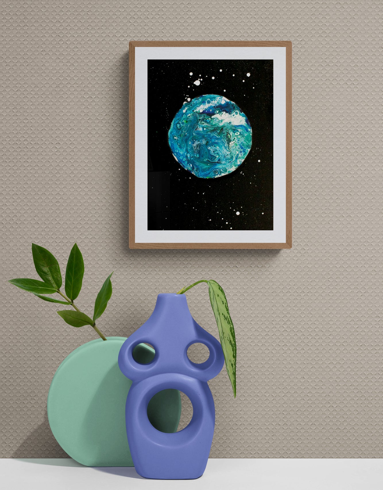 Blue Moon art print in a light wood frame against a textured tan wall, styled with a bold blue and green sculptural vase