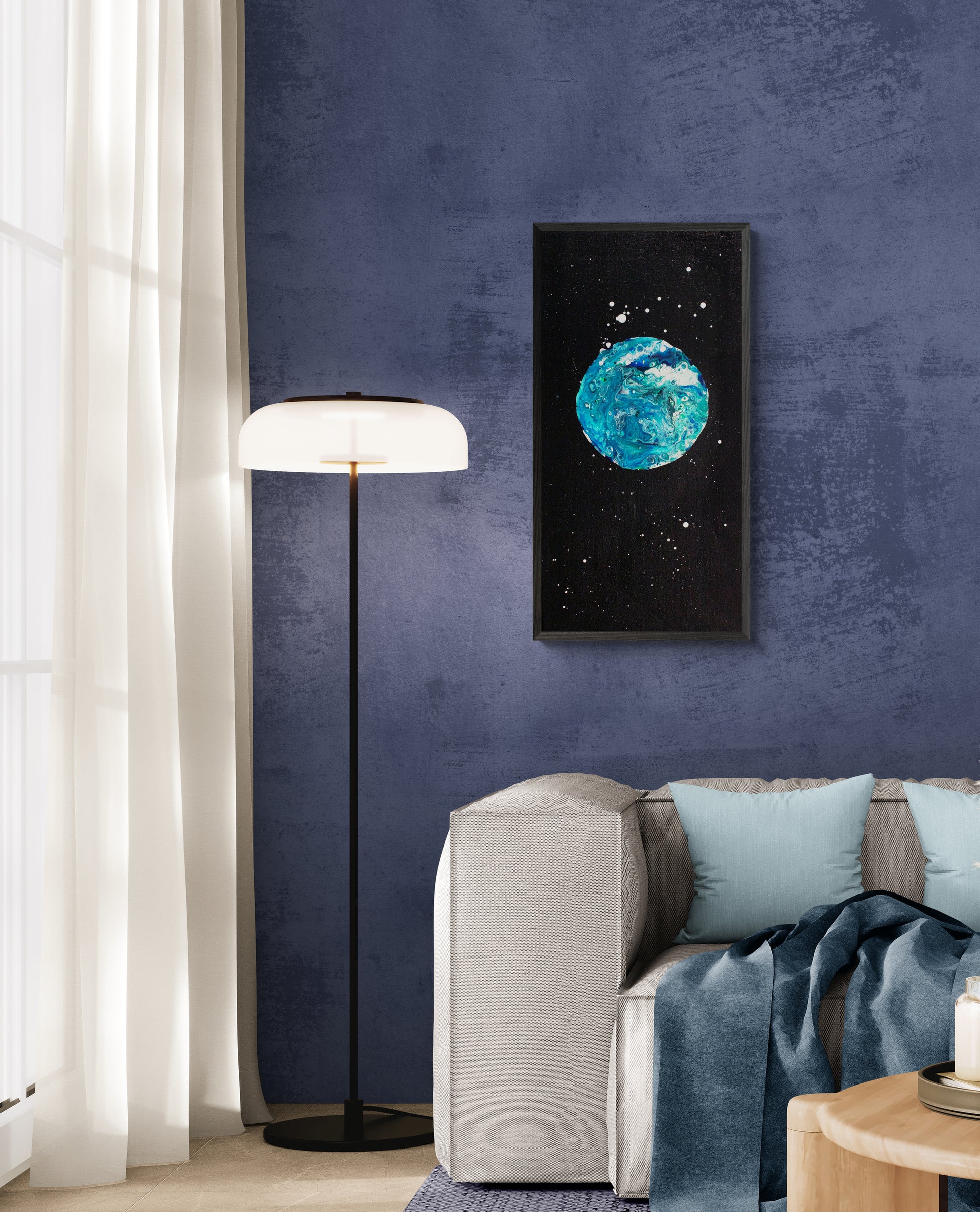 Framed Blue Moon acrylic fluid painting hanging on a moody blue wall beside a floor lamp and gray couch with pale blue pillows.