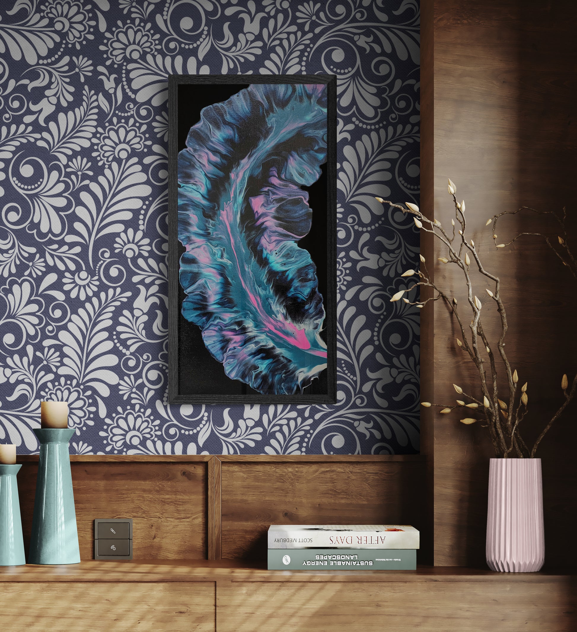 Framed abstract painting with glowing aqua, pink, and deep purple tones displayed on a navy floral wallpapered wall above a wood console with pastel vases, candles, and books.