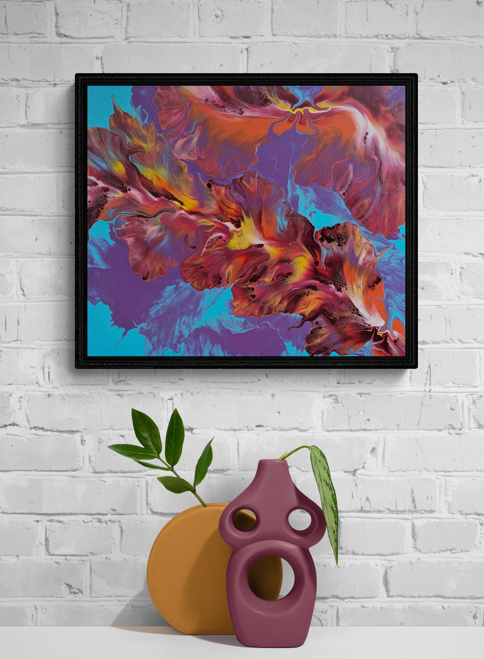 Flames in Bloom original fluid art painting framed in black, styled against a white brick wall with modern sculptural vases.