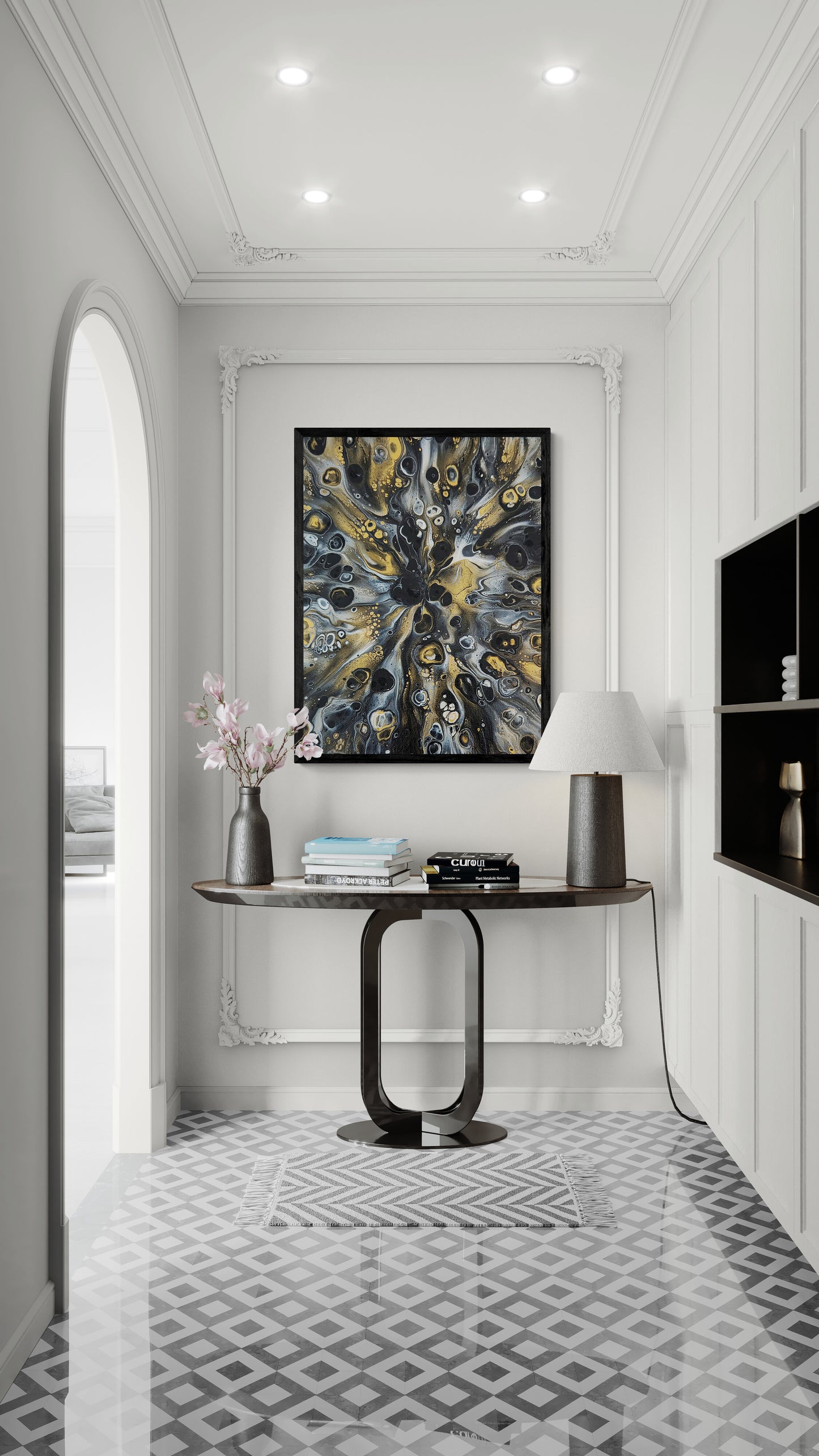Abstract black, gold, and gray fluid art print framed in black, hanging in an elegant white hallway with a console table, books, lamp, and pink flowers