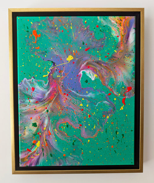 Abstract fluid art painting with swirling purples, pinks, and oranges over a bold green background, accented by vibrant splashes of red, yellow, and black. Displayed in a gold floating frame against a white wall.