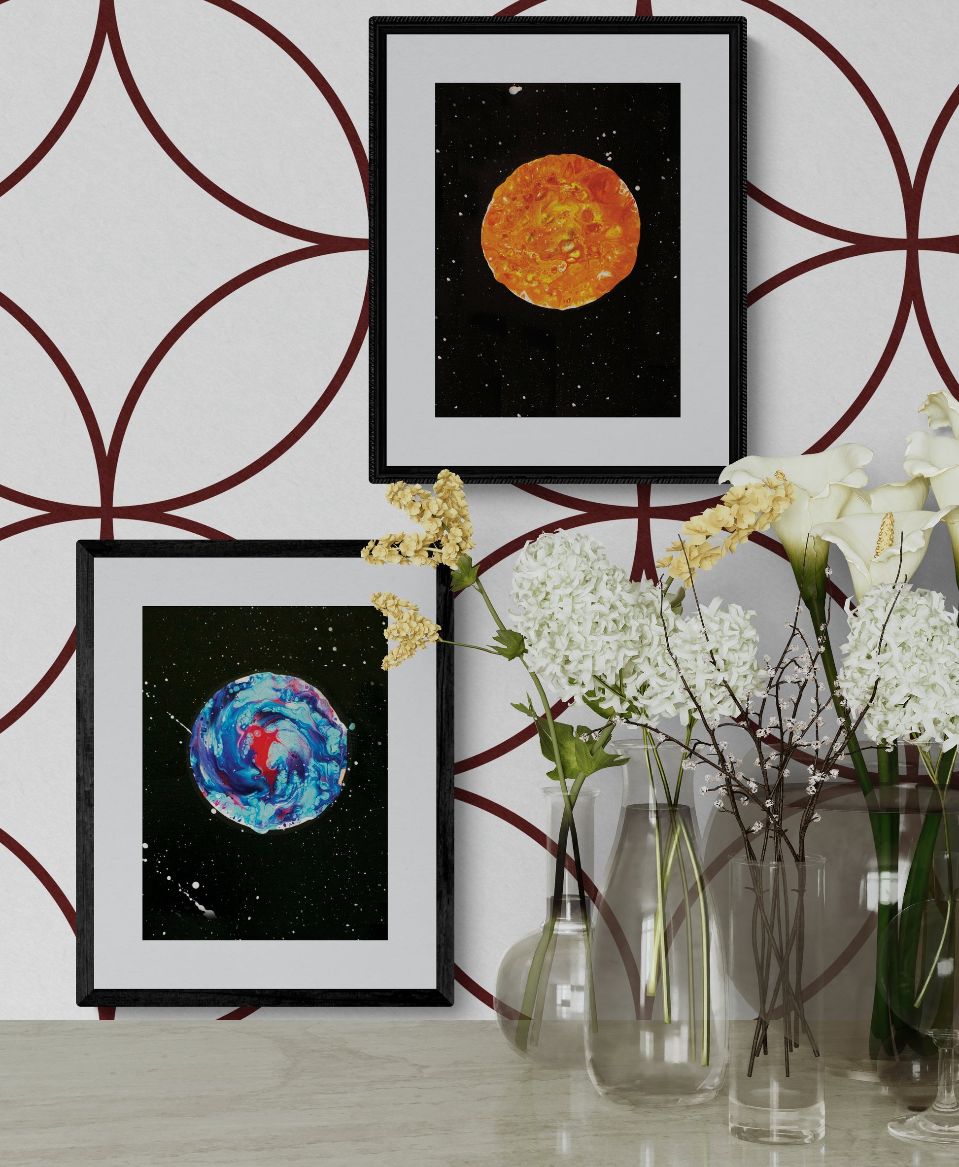 Harvest Moon and Her Majesty The Moon art prints in black frames displayed vertically on a white wall with overlapping maroon circle pattern; surrounded by glass vases with white and yellow flowers.