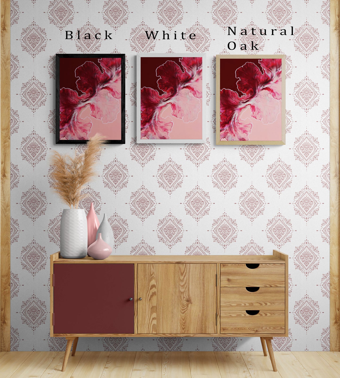 Three Hold the Line canvas prints displayed above a wood sideboard, showing black, white, and natural oak frame options. Each features flowing red and pink fluid art on a blush background.