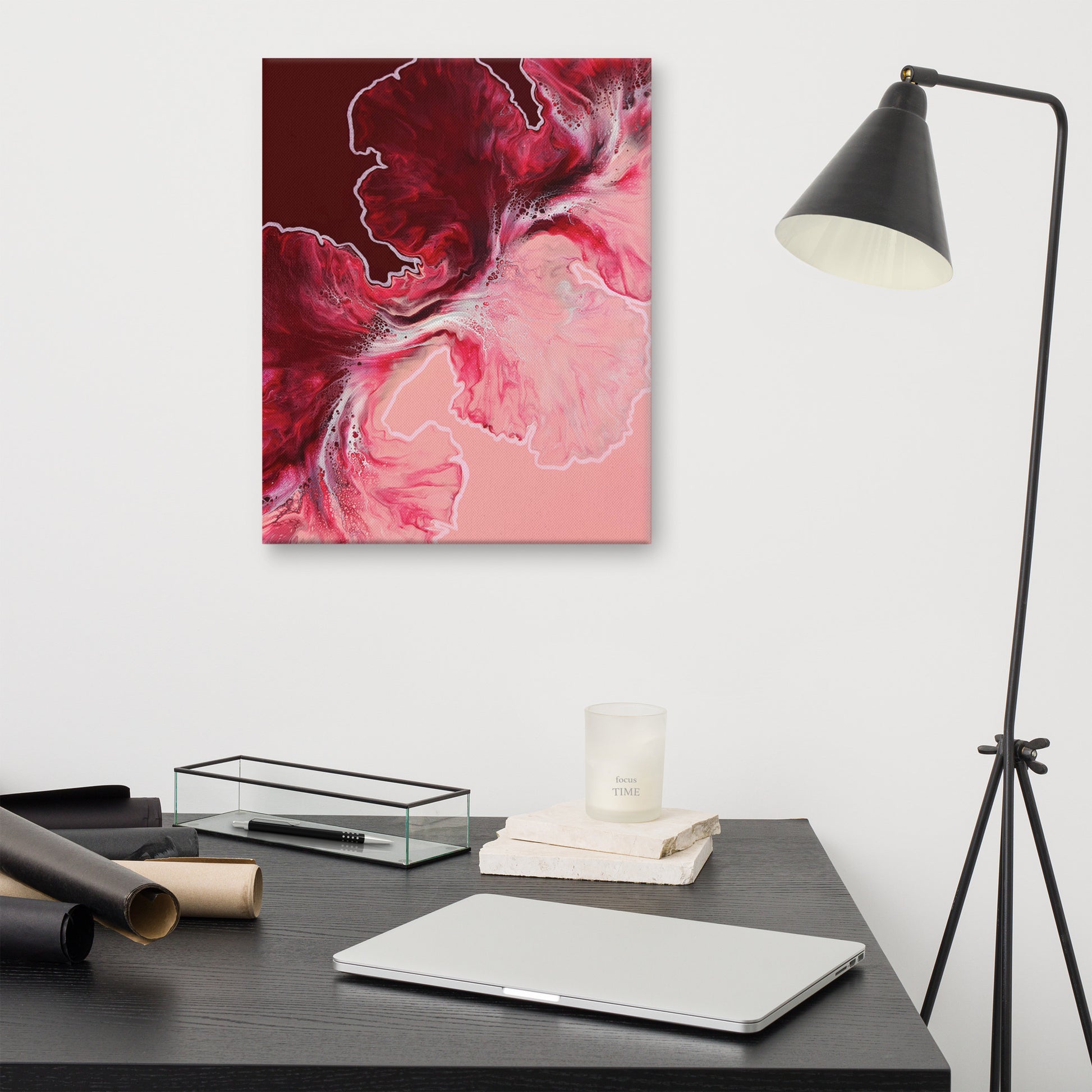 "Hold The Line" acrylic fluid art canvas print without frame, displayed on a white wall above a modern black desk with lamp, showing bold red and pink abstract swirls with white highlights.