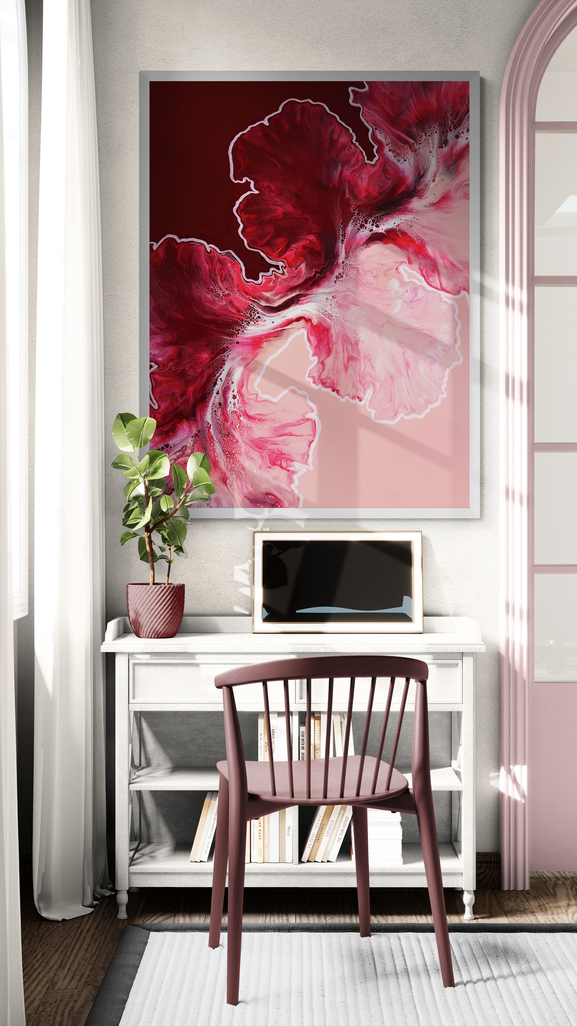 Red and pink abstract fluid art print framed in silver, hanging above a white console with a burgundy chair and potted plant by a window.