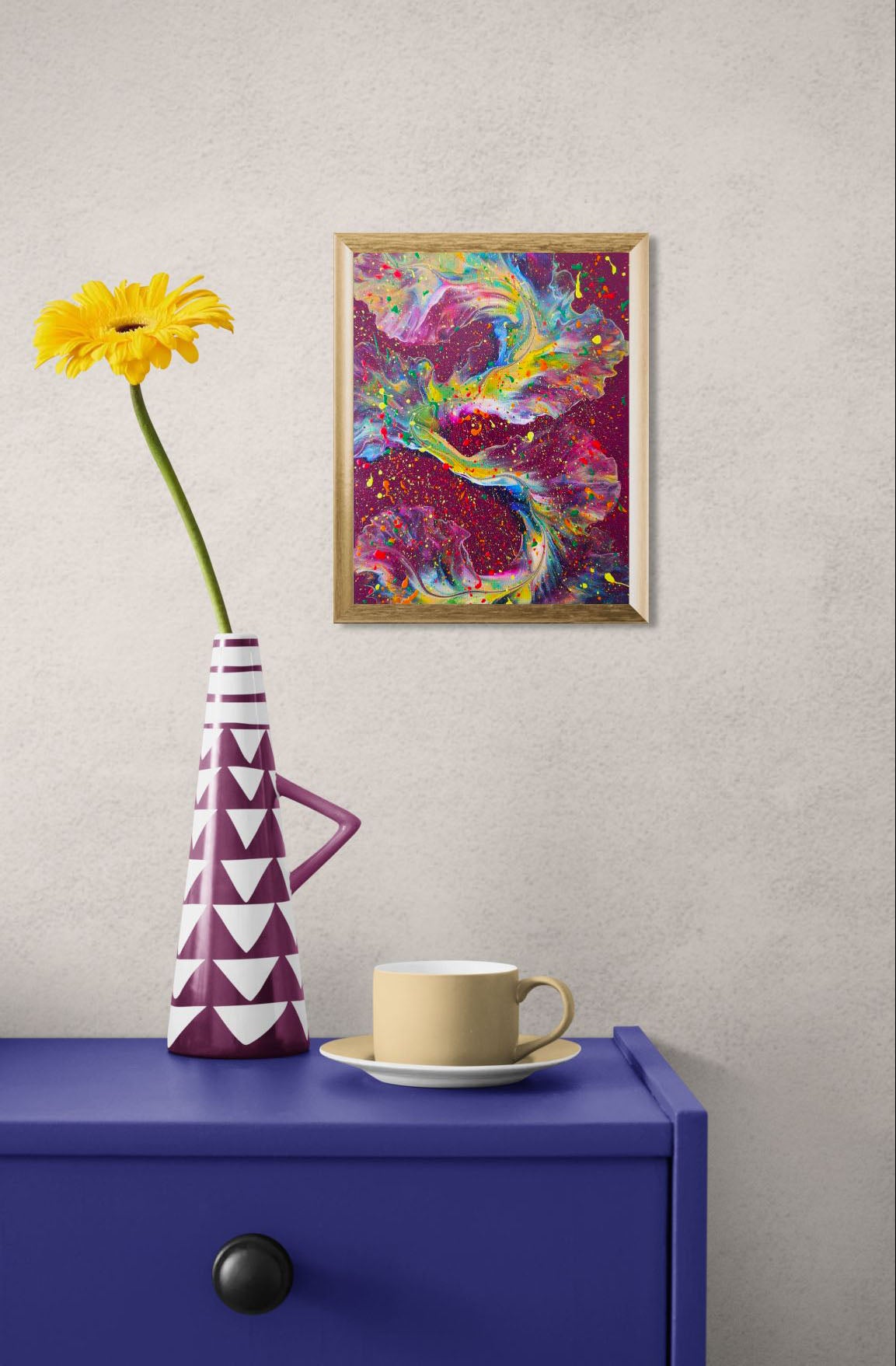'I Wish I Had Your Confidence' painting displayed in a gold frame on a textured wall above a cobalt blue console table, styled with a yellow flower in a magenta and white geometric vase and a mustard yellow teacup.