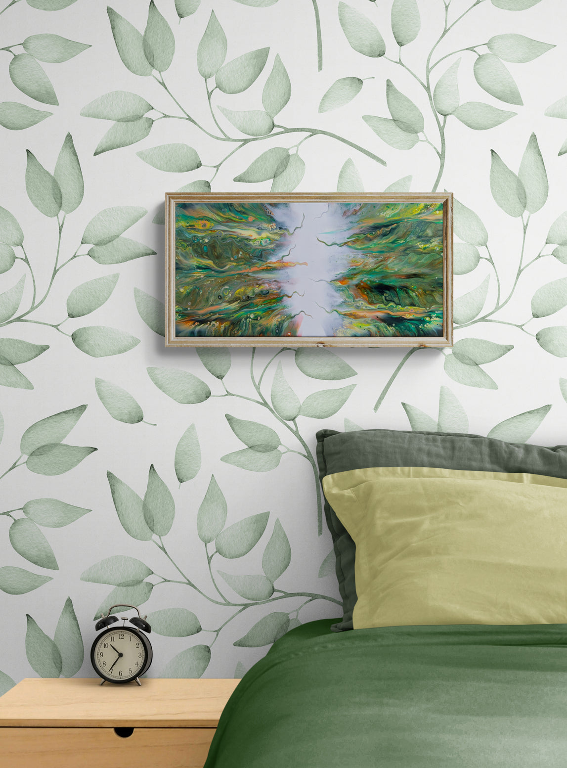 Lush fluid art painting in a light wood frame, styled above a green bed against a leafy botanical wallpaper background.