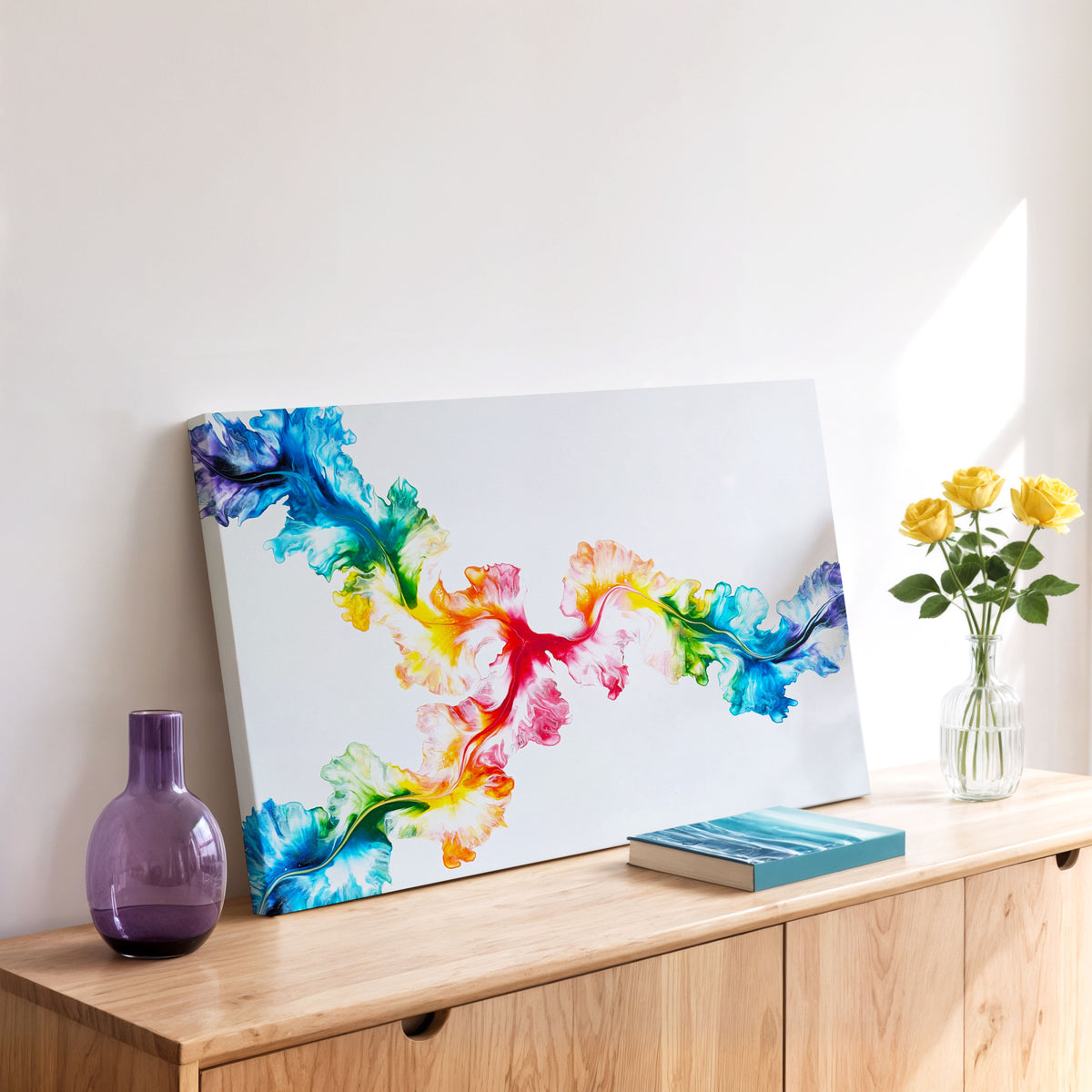 Angle view of Never Dim Your Light, an original fluid painting by Abby May, shown in a room on a wood dresser beside yellow roses.