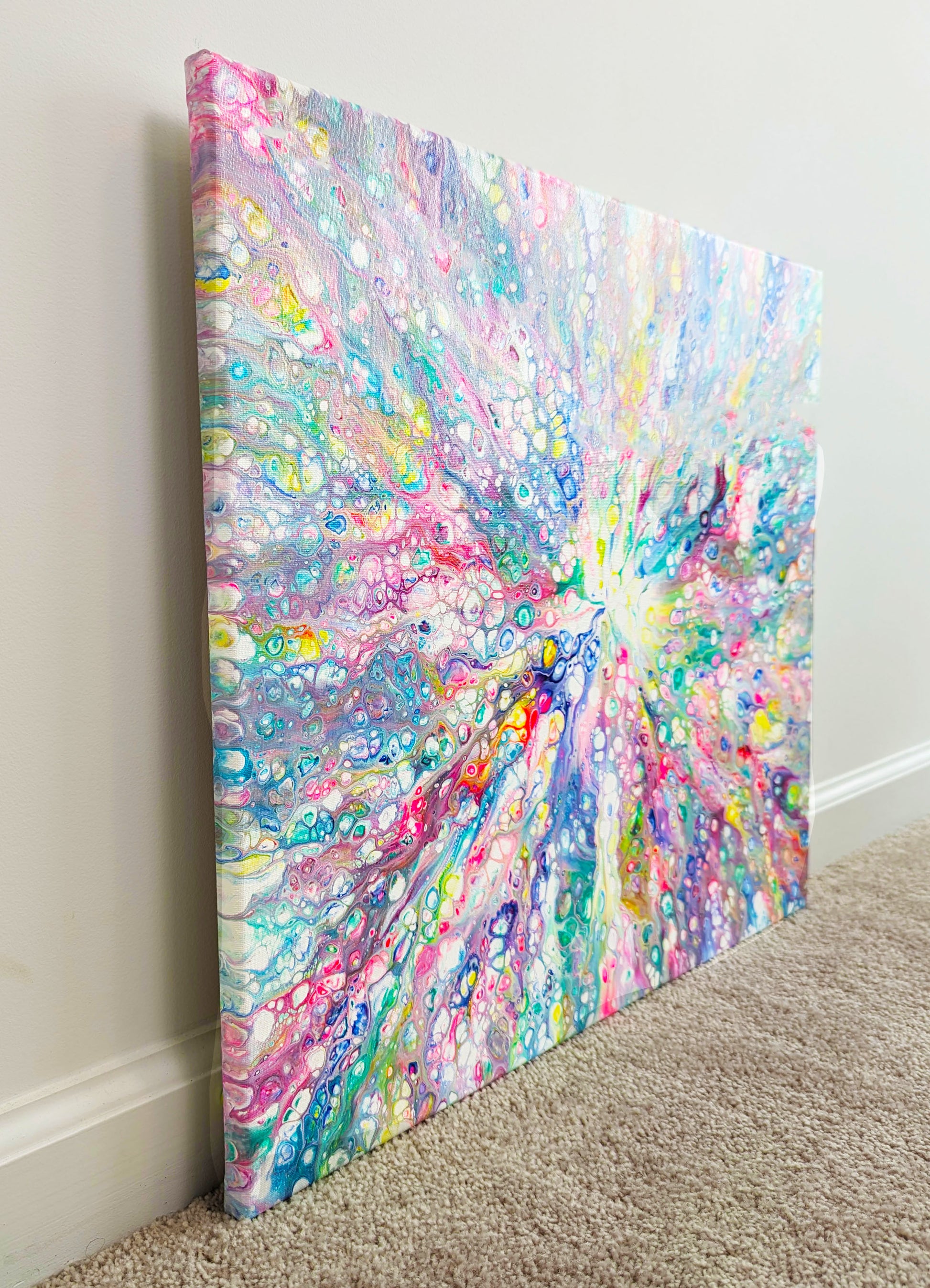 Side view of Rainbow Dragon acrylic fluid art painting, showcasing vibrant rainbow colors and textured canvas against a light wall and carpet