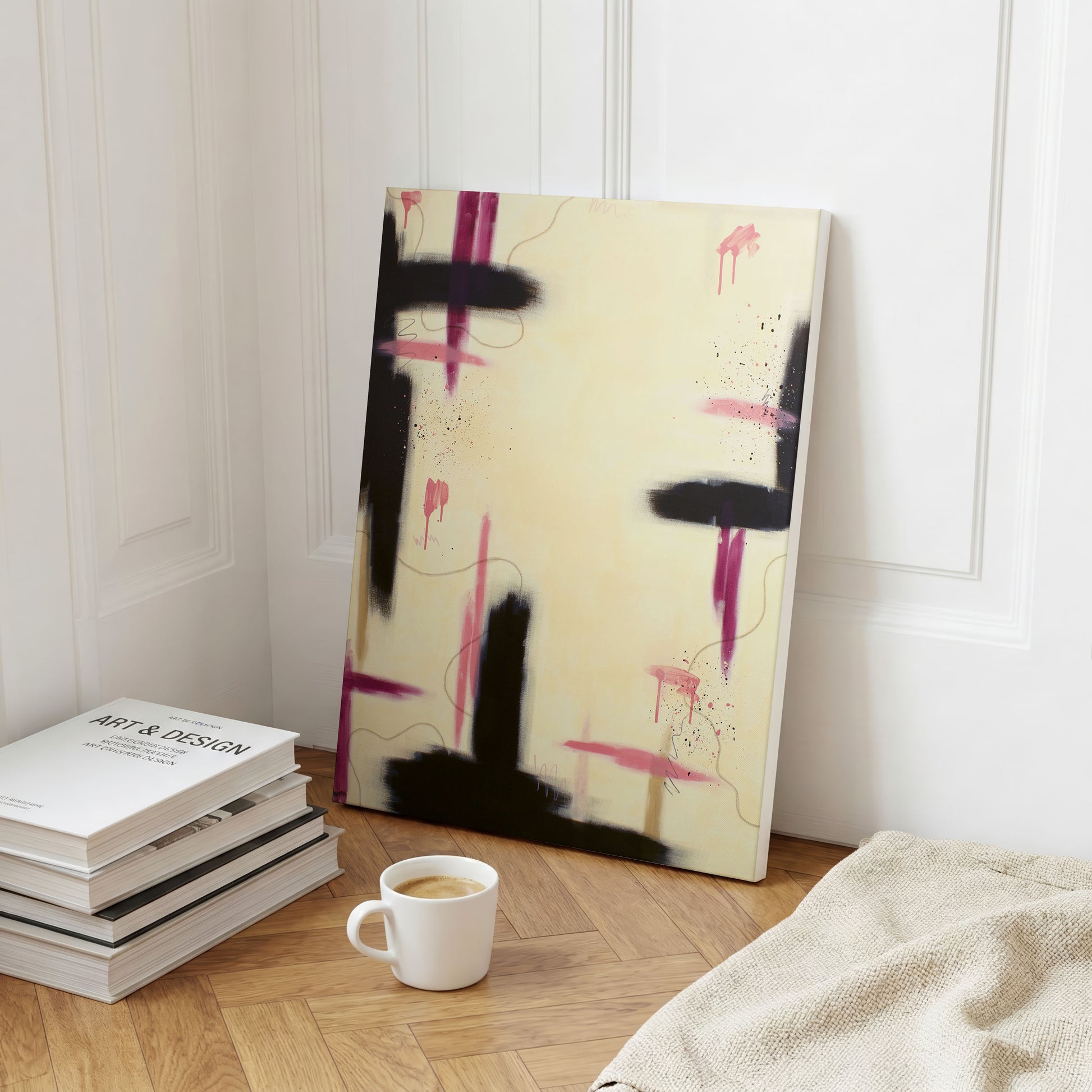 A bedroom lifestyle setting of the canvas print of the painting next to a stack of books, and a tan woven blanket with a white mug of coffee in front. The print sits on a wooden floor sitting against a white wall.