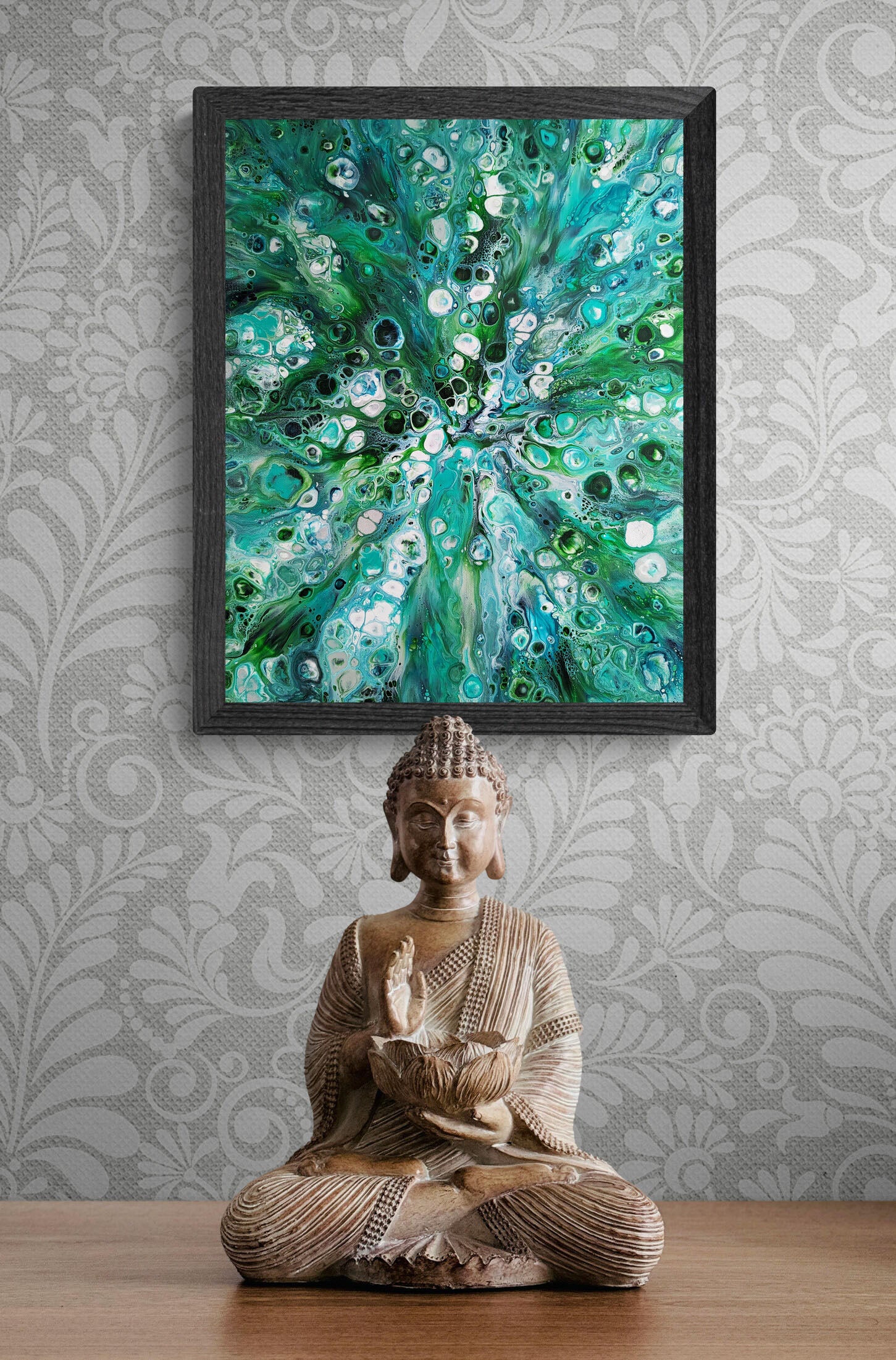 Framed abstract fluid art print titled Sea Maiden displayed above a Buddha statue on a wooden table, artwork featuring swirling turquoise, emerald green, and white patterns.