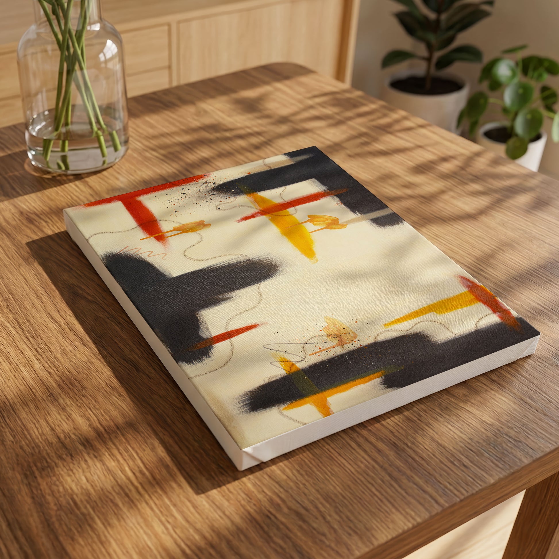 A small canvas print of the painting laying on a wooden table, with a glass vase in the top left. In the background to the left are two potted plants.