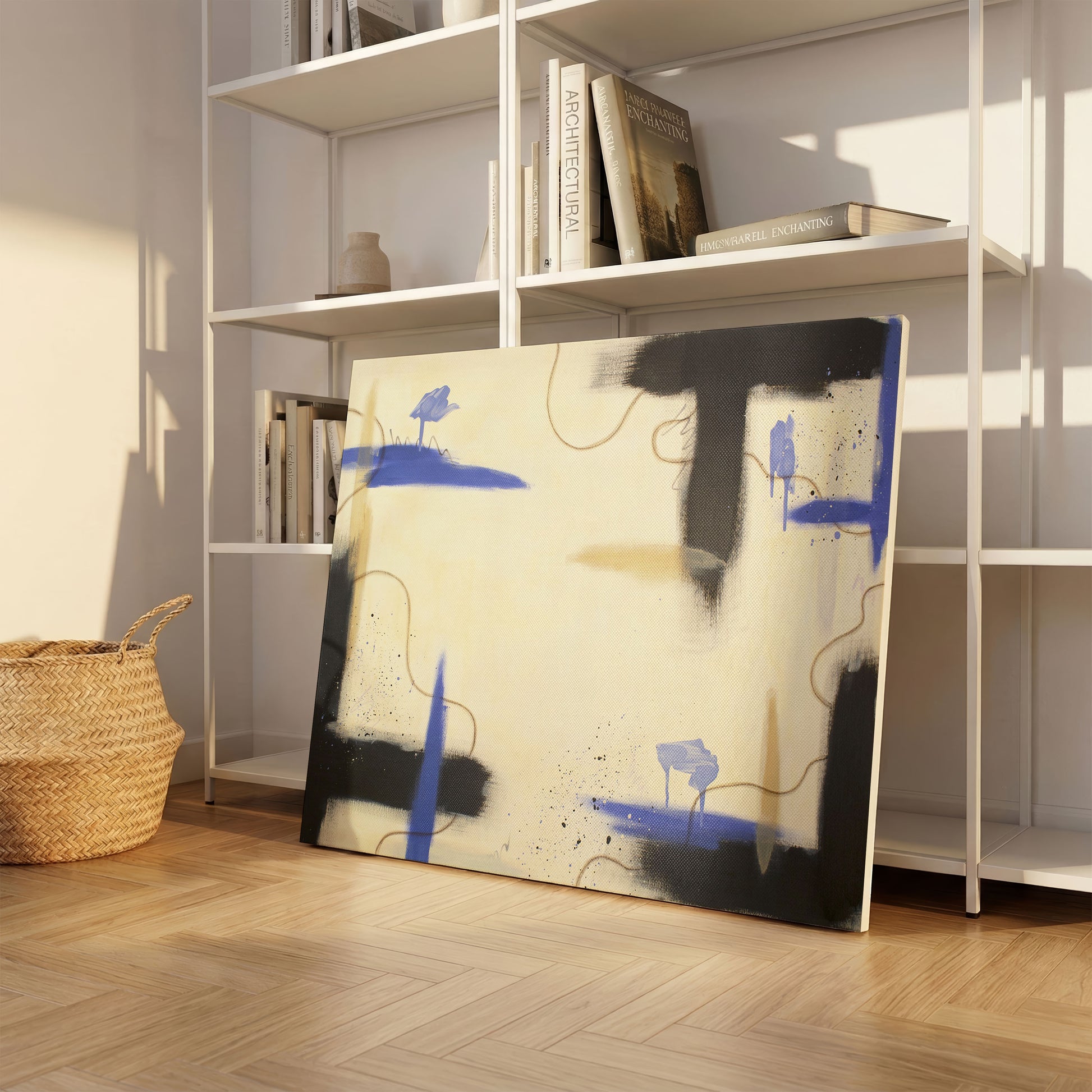 A large canvas print of the painting sitting on a light wooden floor, leaning against a simple stack of white shelving. On the shelves are various books, and a light grey decorative vase. On the left is a brown woven basket.