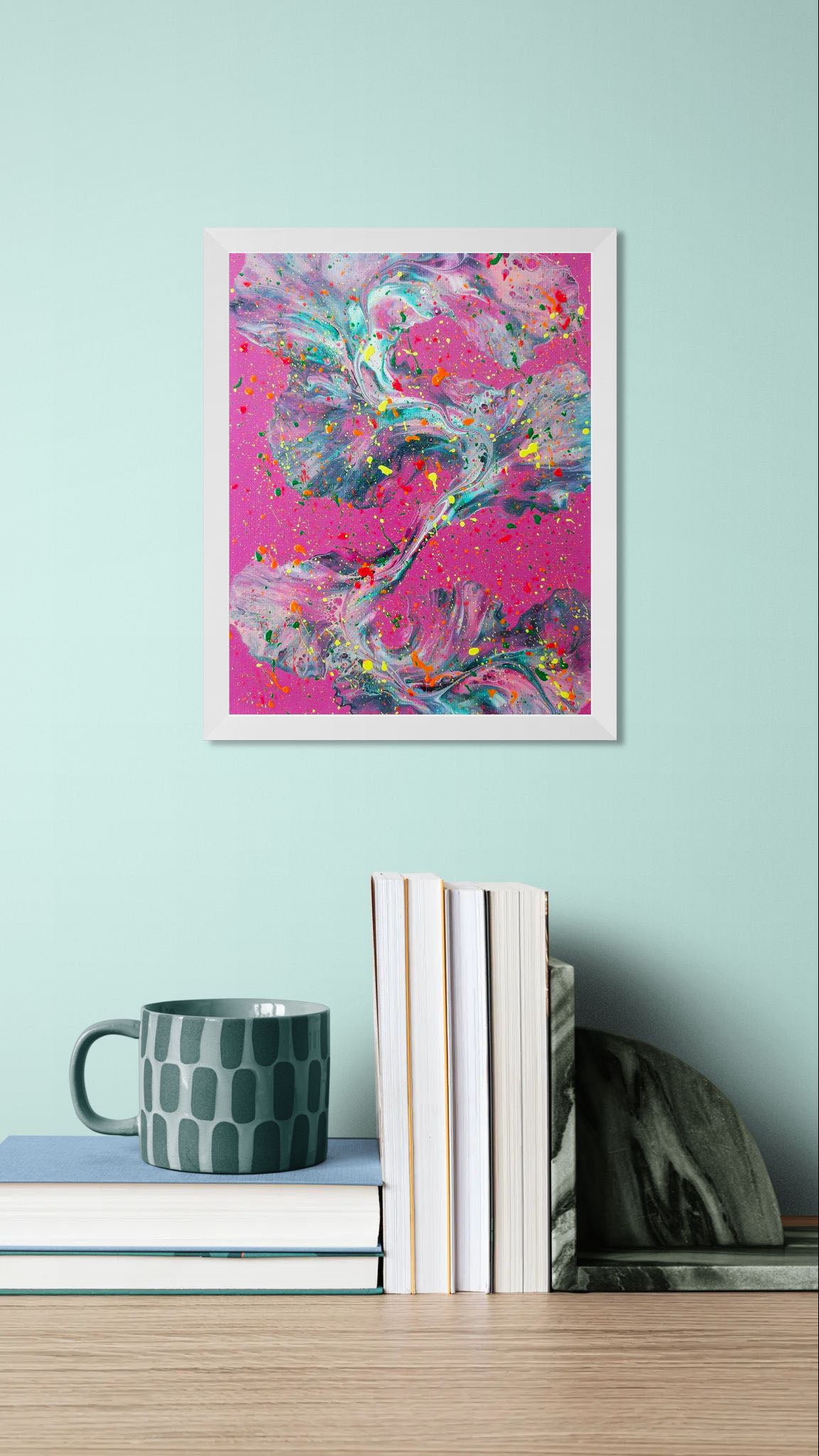 'That’s a Bold Choice' painting in a white frame on a mint green wall above a stack of books and a patterned gray-green mug for a vibrant, cozy aesthetic.